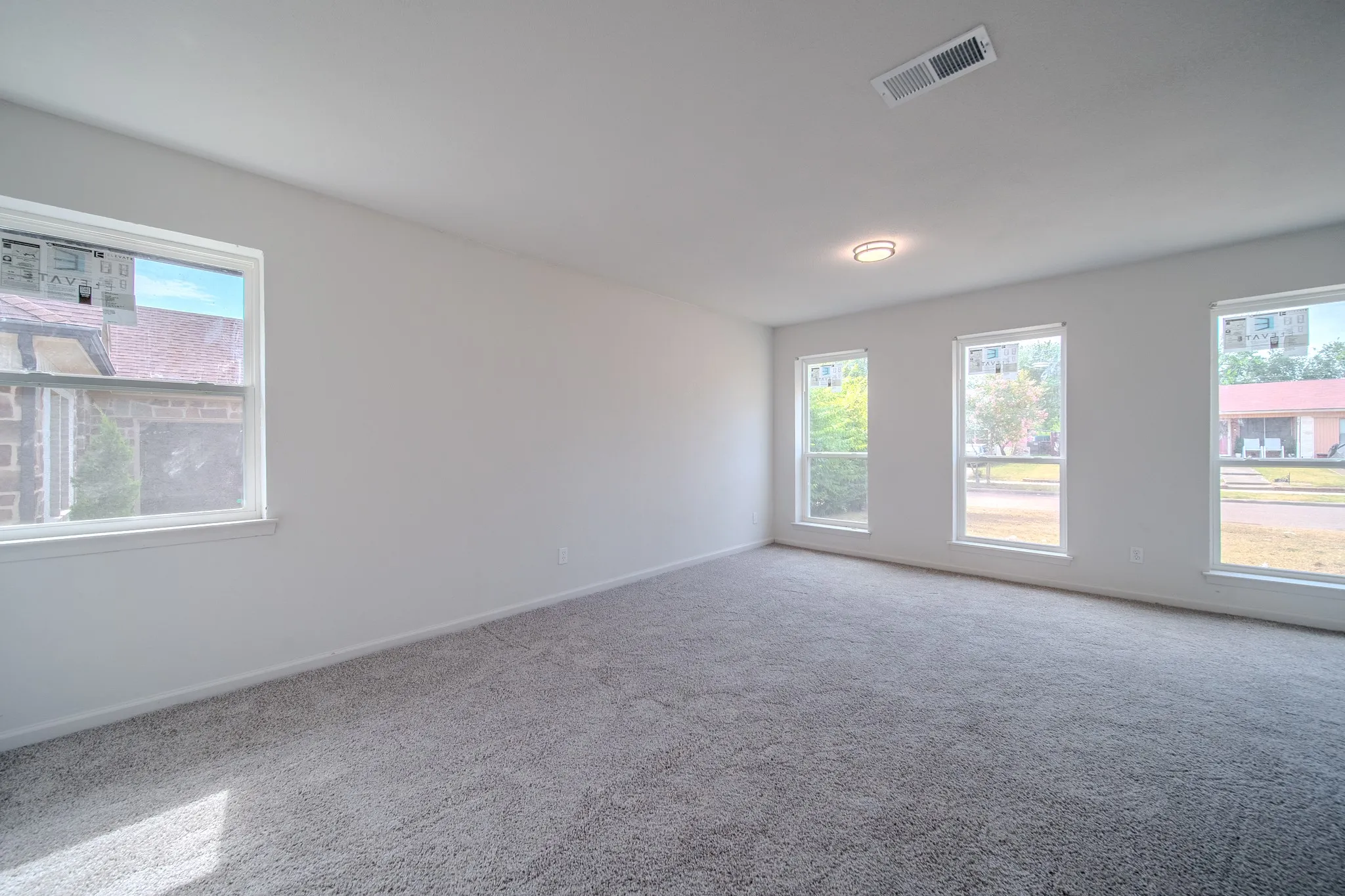 Recessed lighting, light gray carpeting, multiple windows, and a flush mount ceiling fixture