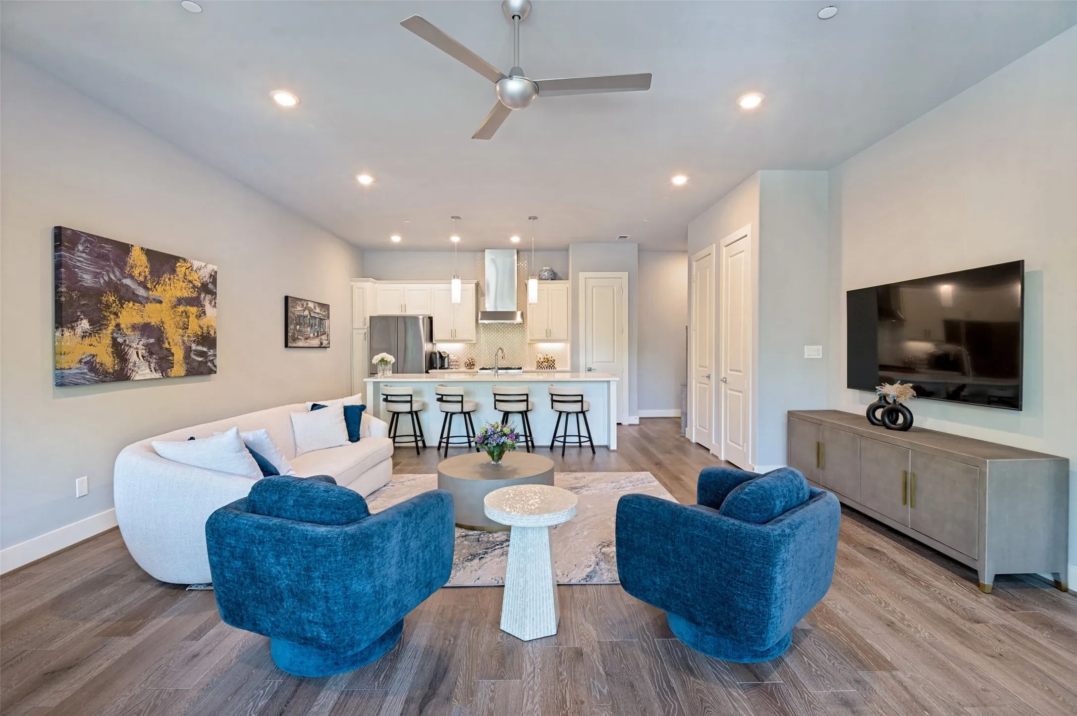 Open-concept living area with wood-finish flooring, recessed lighting, and a modern ceiling fan