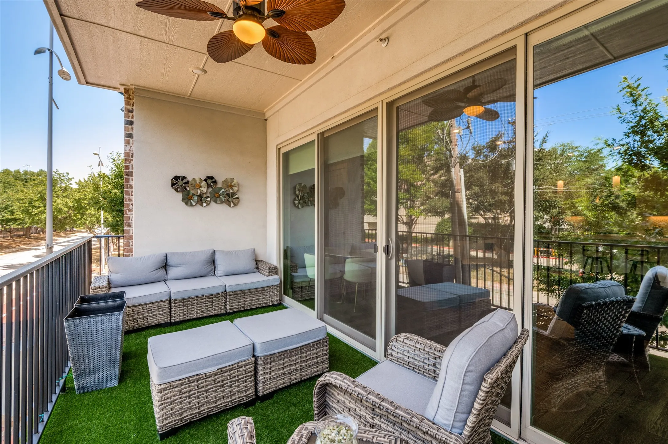 A wall of sliding glass doors opens to the covered terrace with ceiling fan and turf cover