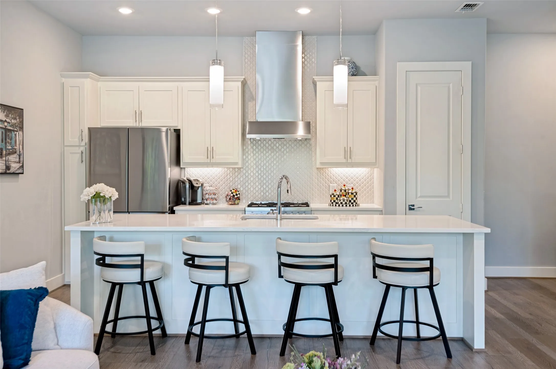 Kitchen featuring white shaker cabinetry, stainless steel appliances, a white island, pendant lighting, and wood- flooring