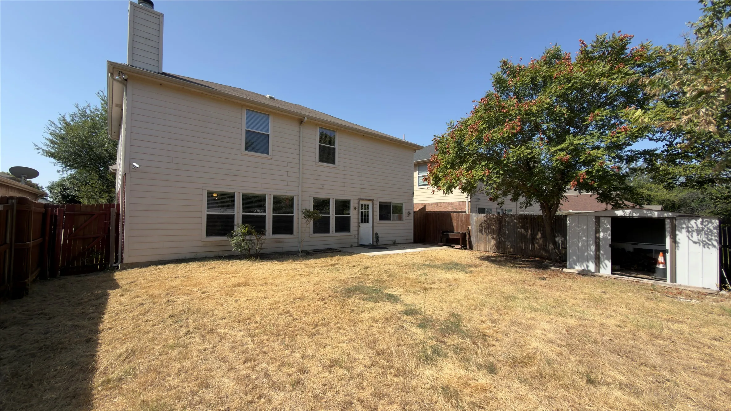 Two-story exterior with multiple windows, a rear entry door, and a detached storage shed