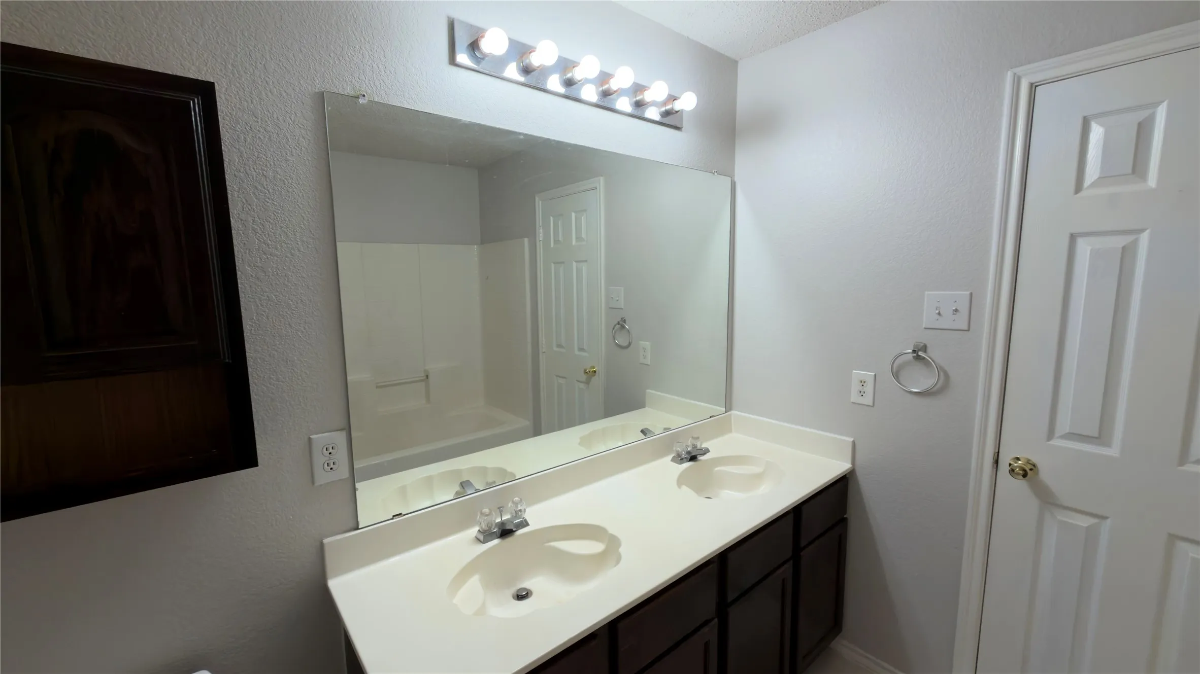 Dual vanity with integrated sinks, a large wall-mounted mirror, and a multi-bulb lighting fixture