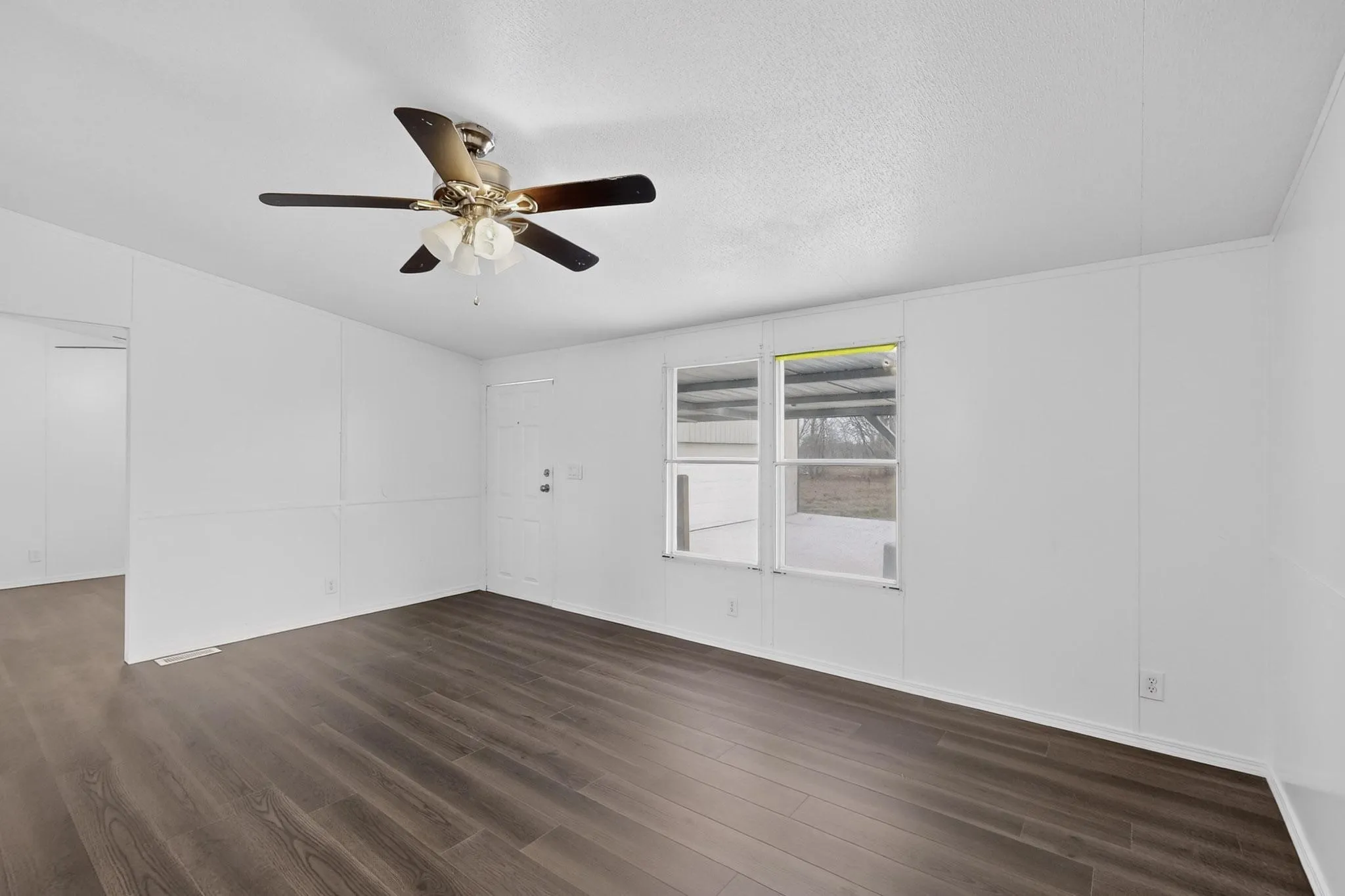 Unfurnished room with dark wood-style flooring, ceiling fan, and a textured ceiling