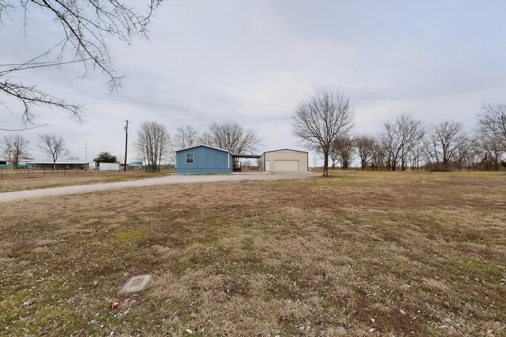 View of grassy yard featuring a garage, an outdoor structure, and driveway