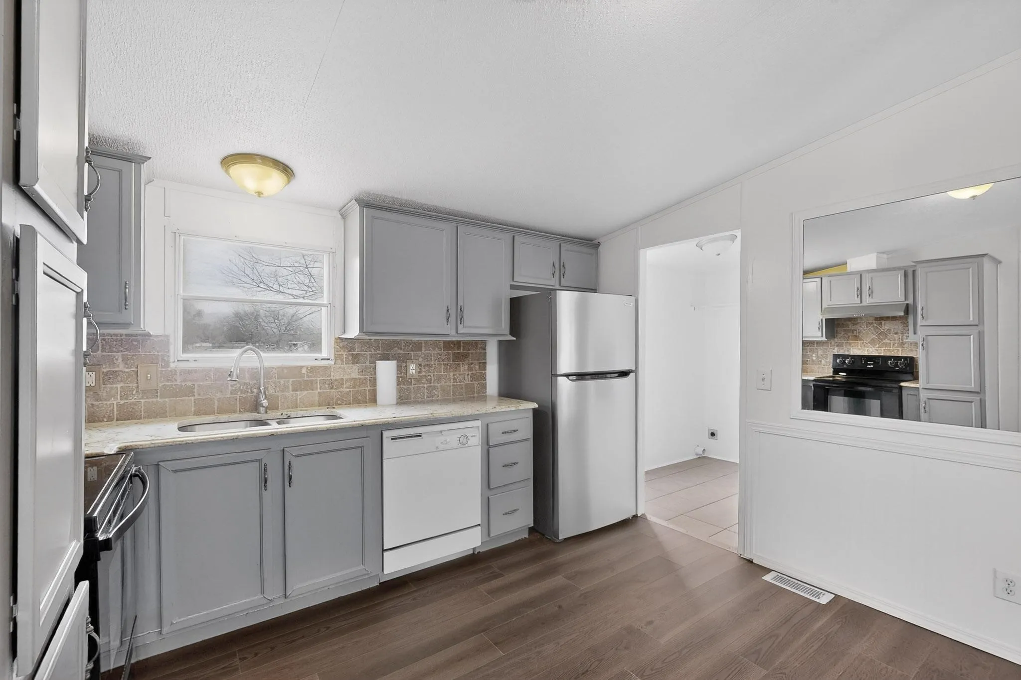 Kitchen featuring gray cabinetry, tasteful backsplash, stainless steel appliances, and vaulted ceiling