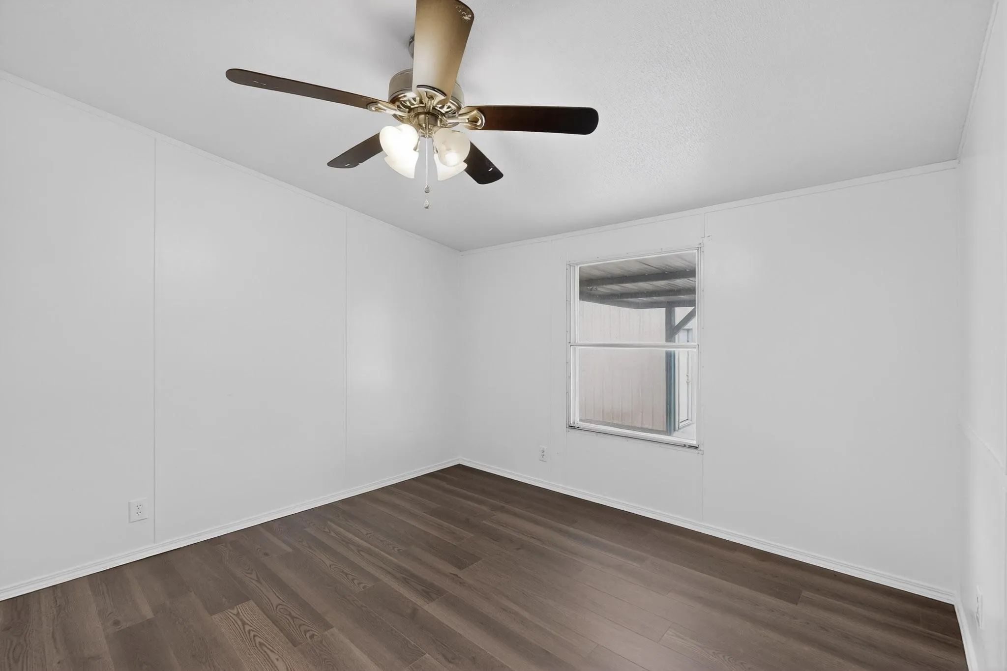 Empty room featuring a ceiling fan and dark wood-style floors
