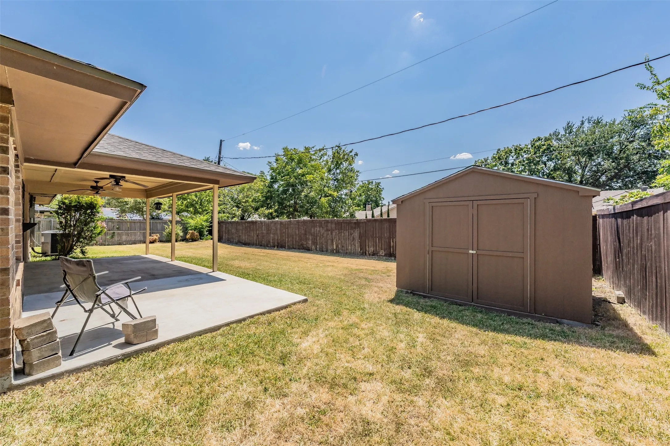 Covered patio with concrete flooring, dual ceiling fans, and brick exterior