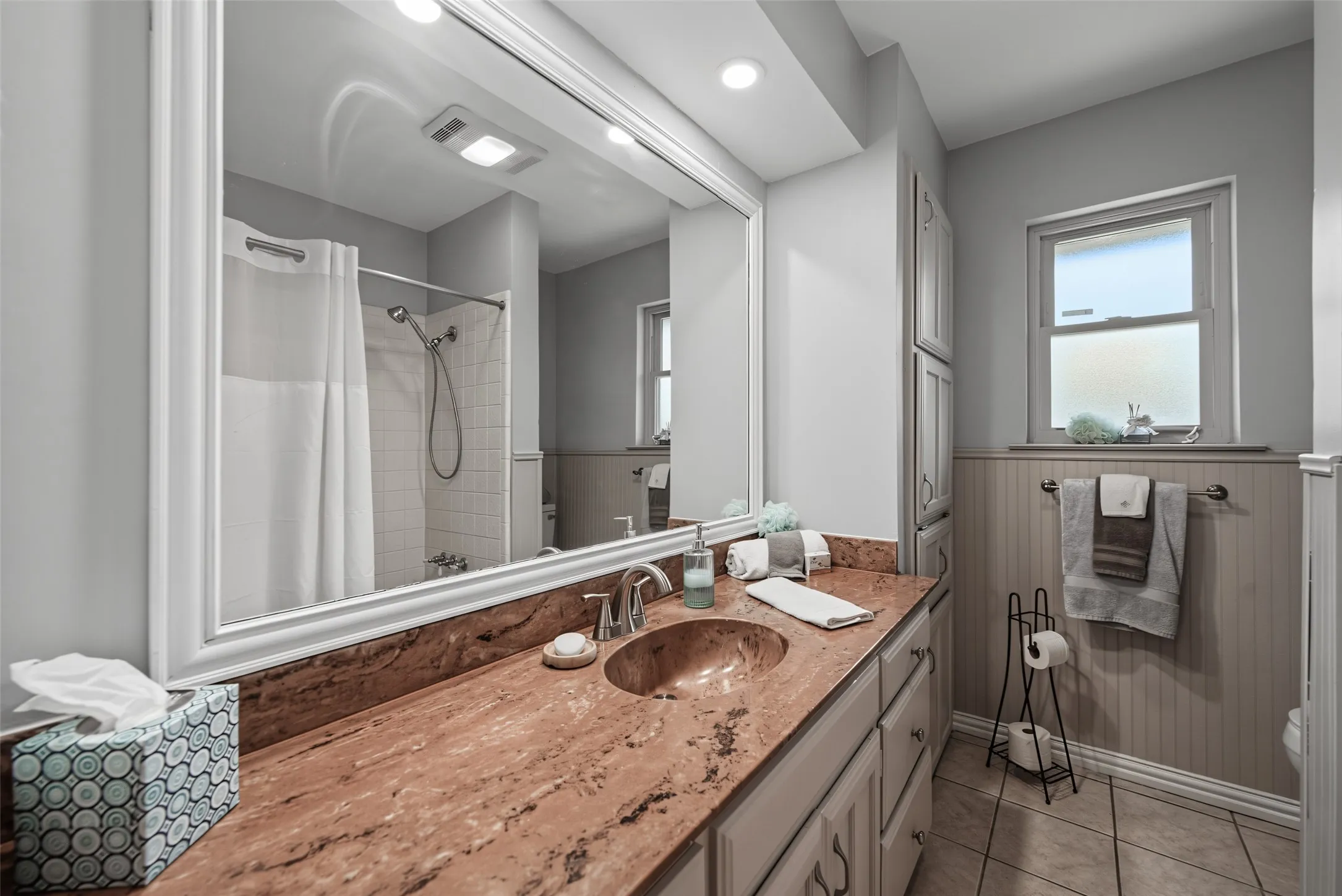 Guest bath: Vanity with an integrated sink, polished chrome faucet, and a large framed mirror