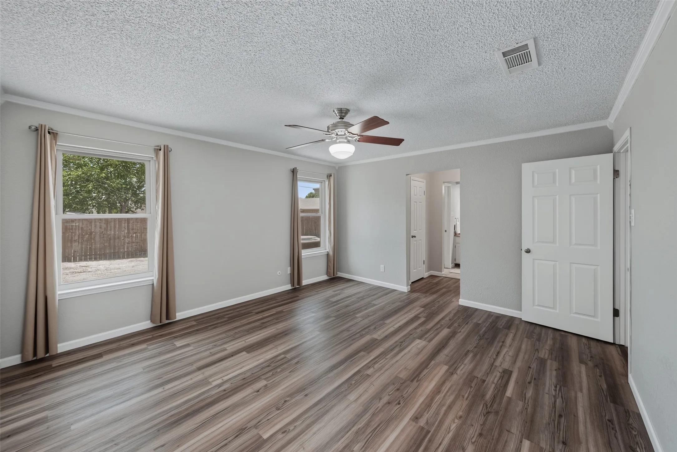 Bedroom 2: Spacious room featuring luxury vinyl flooring, light grey walls, and a ceiling fan