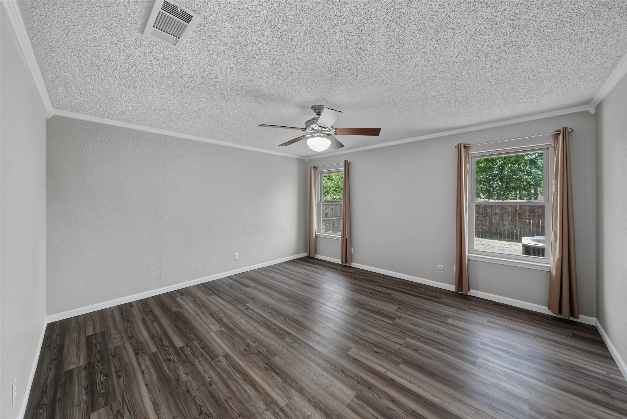 Bedroom 2: Spacious room featuring luxury vinyl plank flooring, two windows, and a ceiling fan with integrated lighting