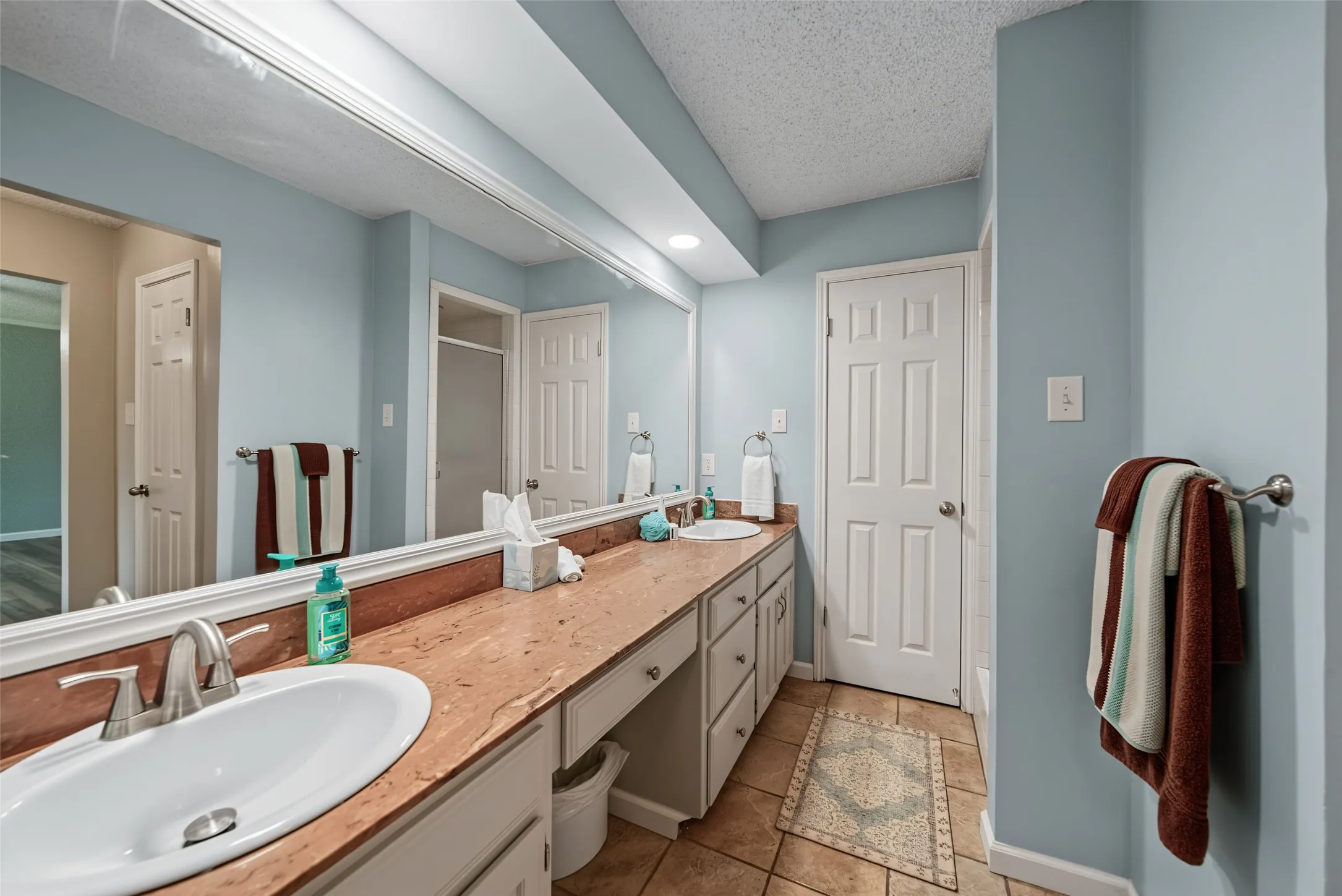 Primary bath: Dual vanity with undermount sinks, extensive countertop space, and integrated storage cabinetry