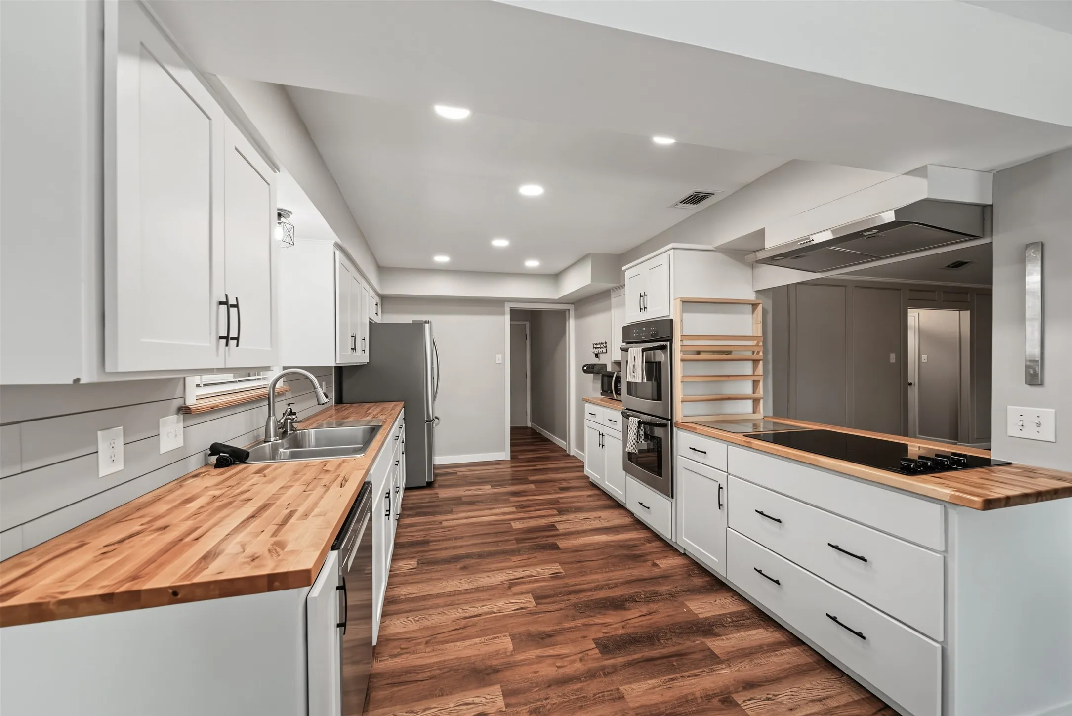 Kitchen featuring luxury vinyl plank flooring, white cabinetry, wood countertops, and stainless steel appliances