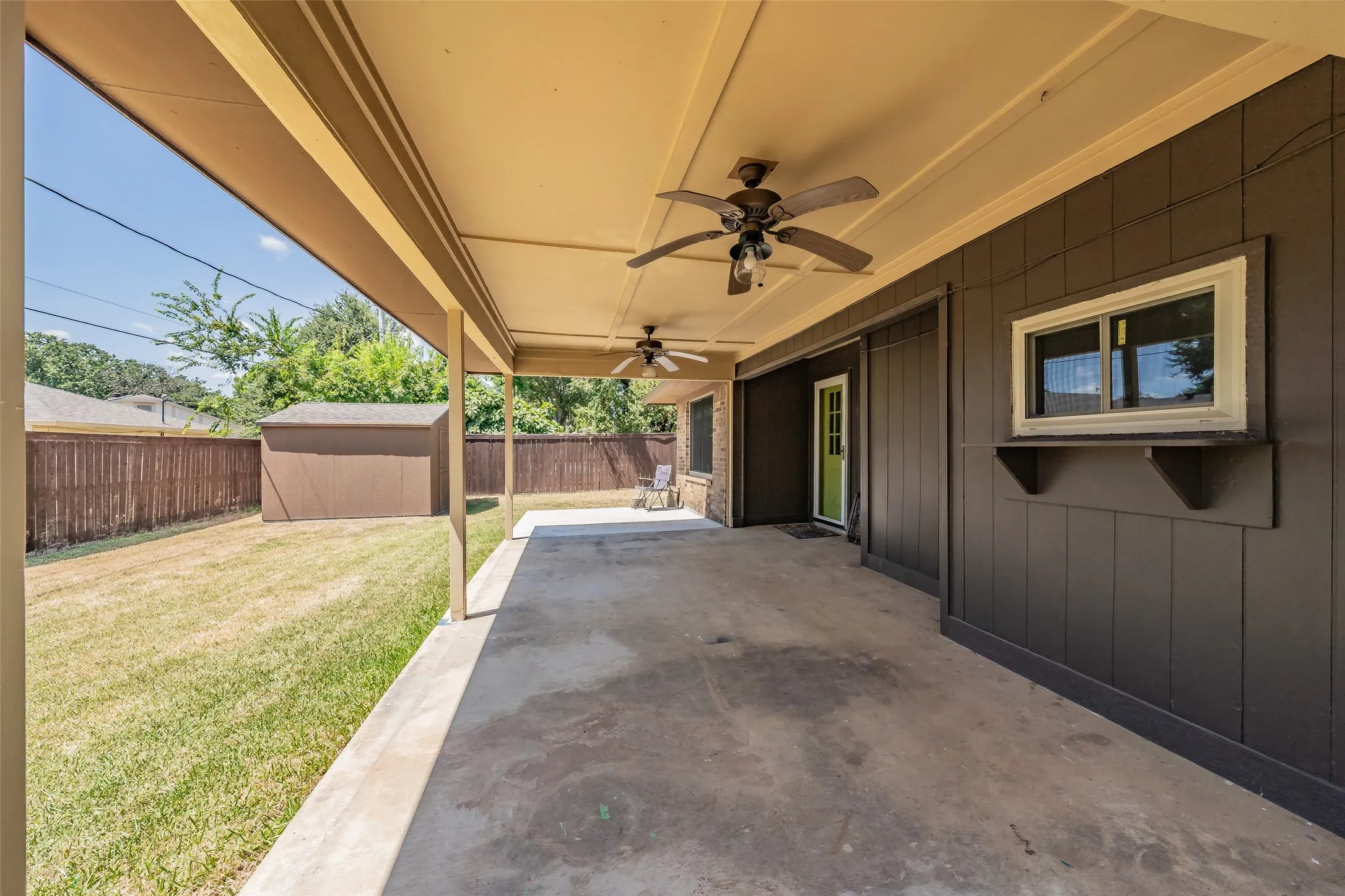 Covered concrete patio with ceiling fans and a built-in window shelf