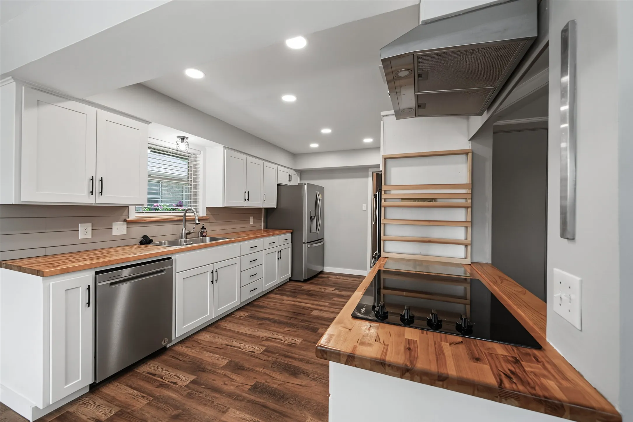 Kitchen featuring white shaker cabinetry, butcher block countertops, stainless steel appliances, recessed lighting, and luxury vinyl plank flooring