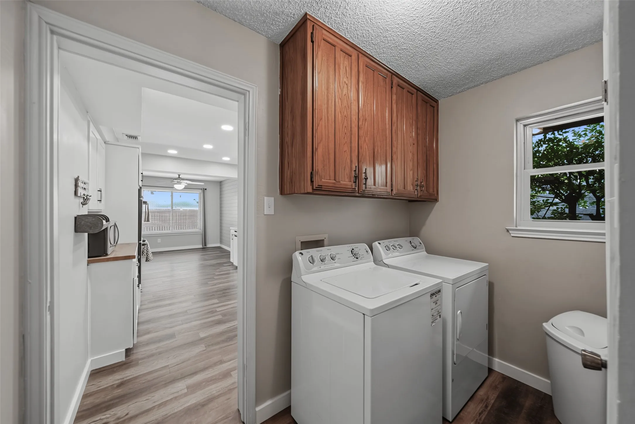 Luxury vinyl flooring, overhead cabinetry, and a window providing natural light