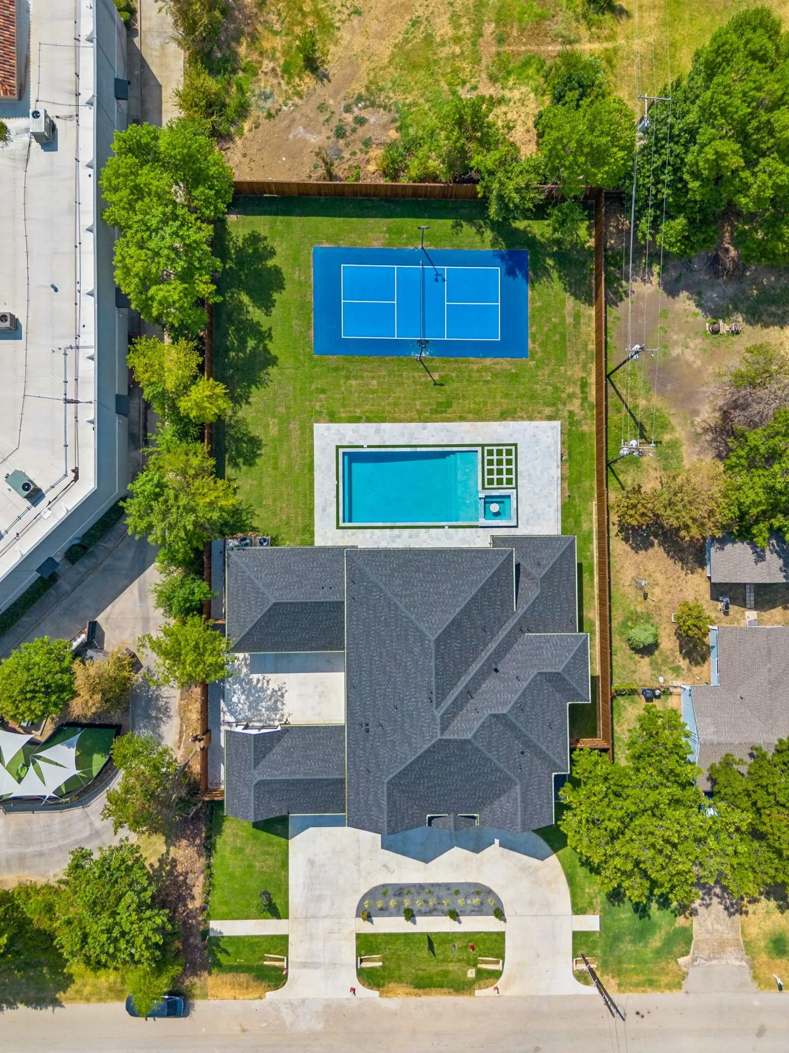Expansive backyard featuring a manicured lawn, a full-size tennis court, and an in-ground swimming pool with an integrated spa