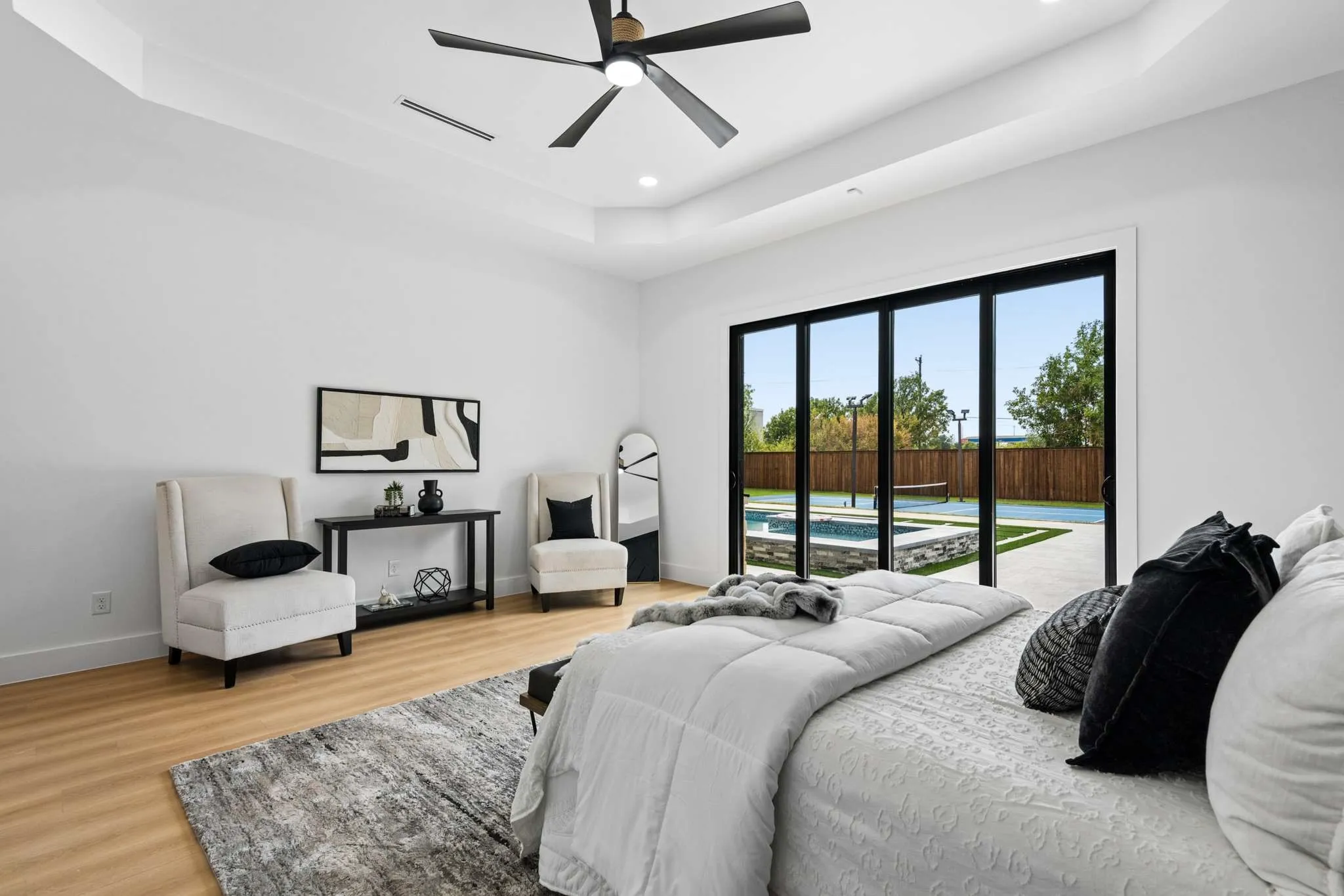 Tray ceiling with recessed lighting, wood-finish flooring, and black-framed sliding glass doors