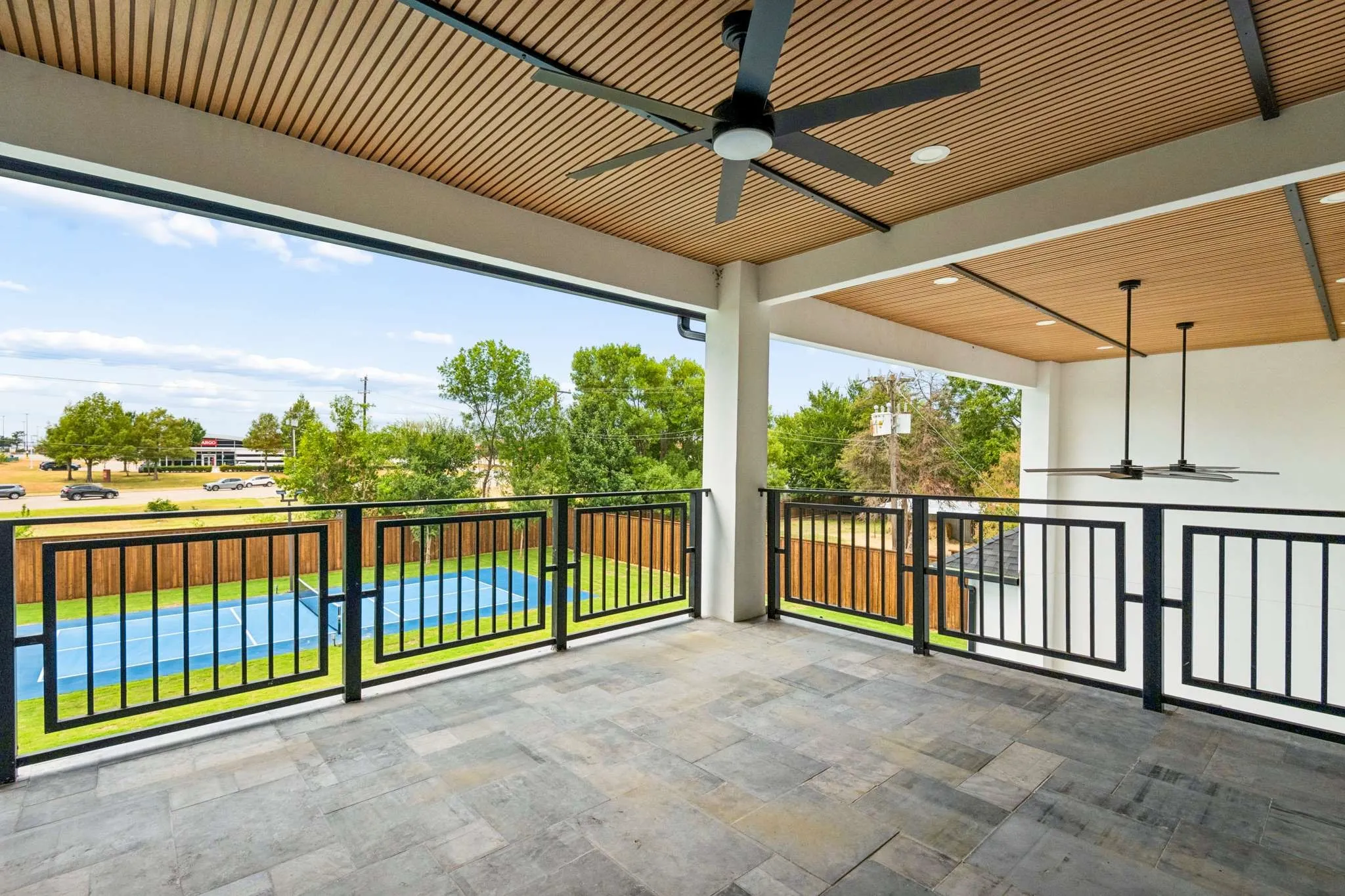 Expansive balcony featuring a textured tile floor, wood-slat ceiling, recessed lighting, and black ceiling fans
