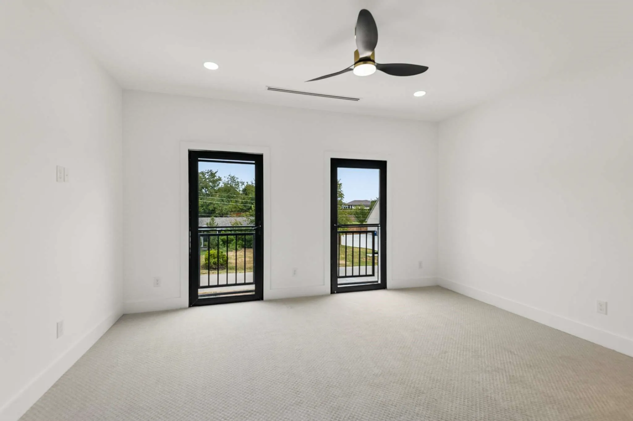 Recessed lighting, modern ceiling fan, two full-light doors with black frames and integrated grilles, and light-toned carpet