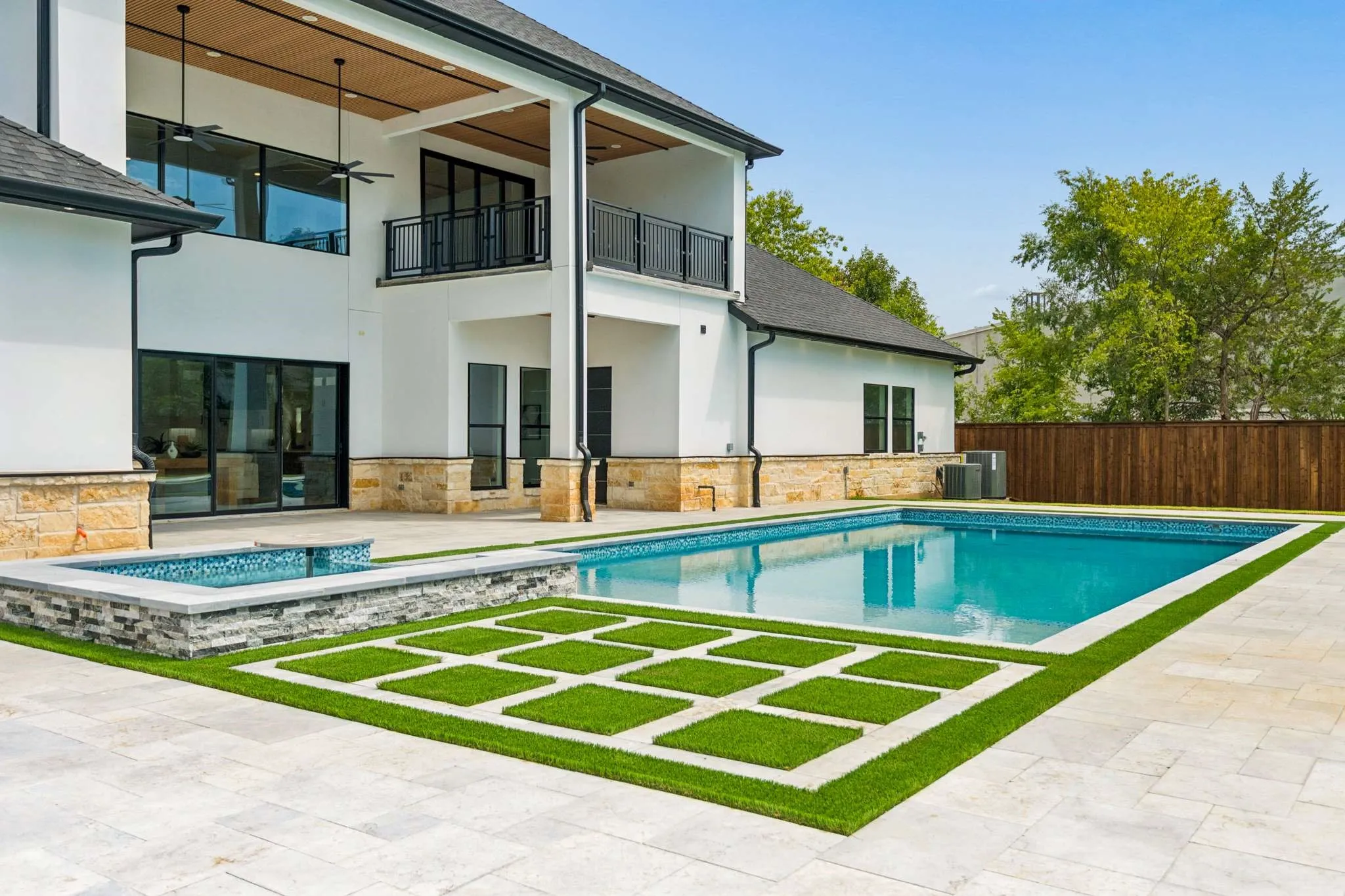 Outdoor living area featuring a swimming pool, integrated spa, and expansive patio with artificial turf accents