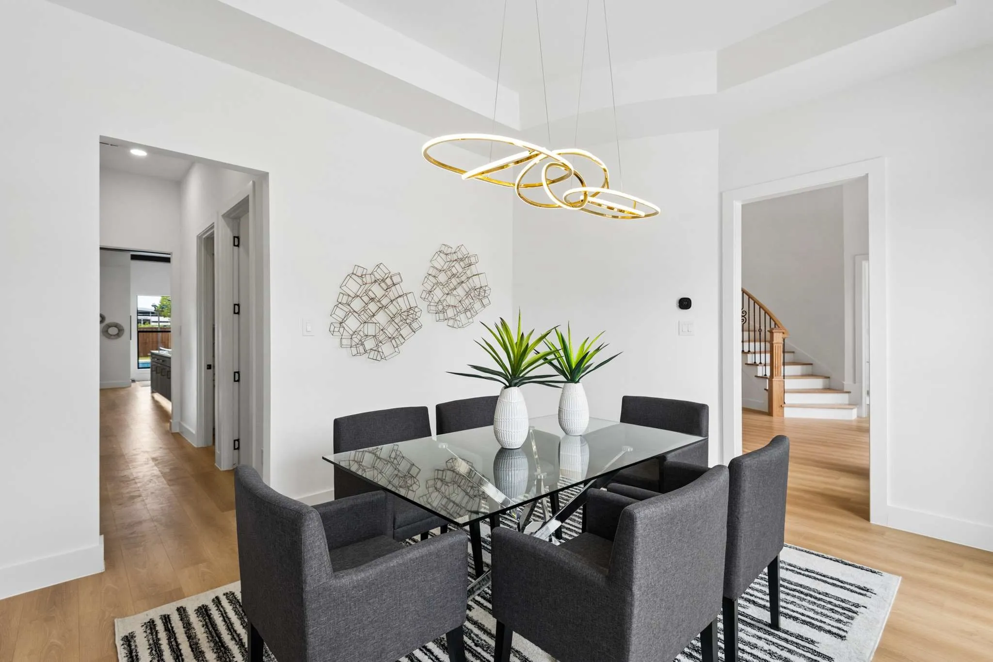 Dining area featuring a contemporary chandelier, light wood-finish flooring, and crisp white walls