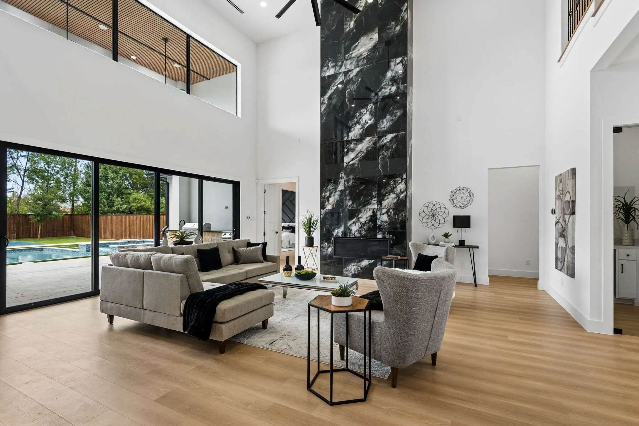 Two-story living area with high ceilings, a grand fireplace with floor-to-ceiling stone-look surround, and wood-finish flooring