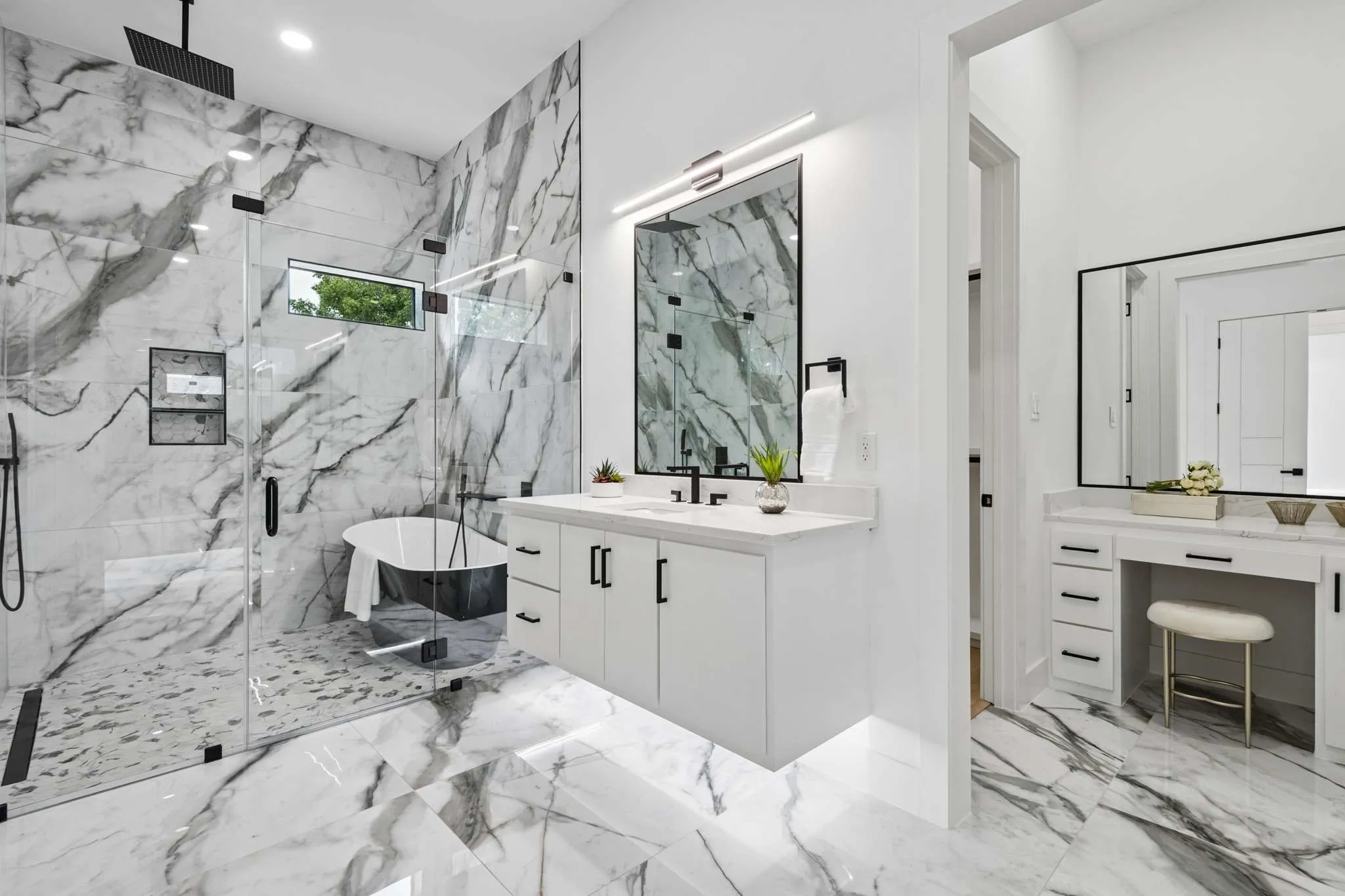 Walk-in shower with clear glass enclosure, freestanding soaking tub, dual-sink vanity with quartz countertop, and large format marble-look flooring