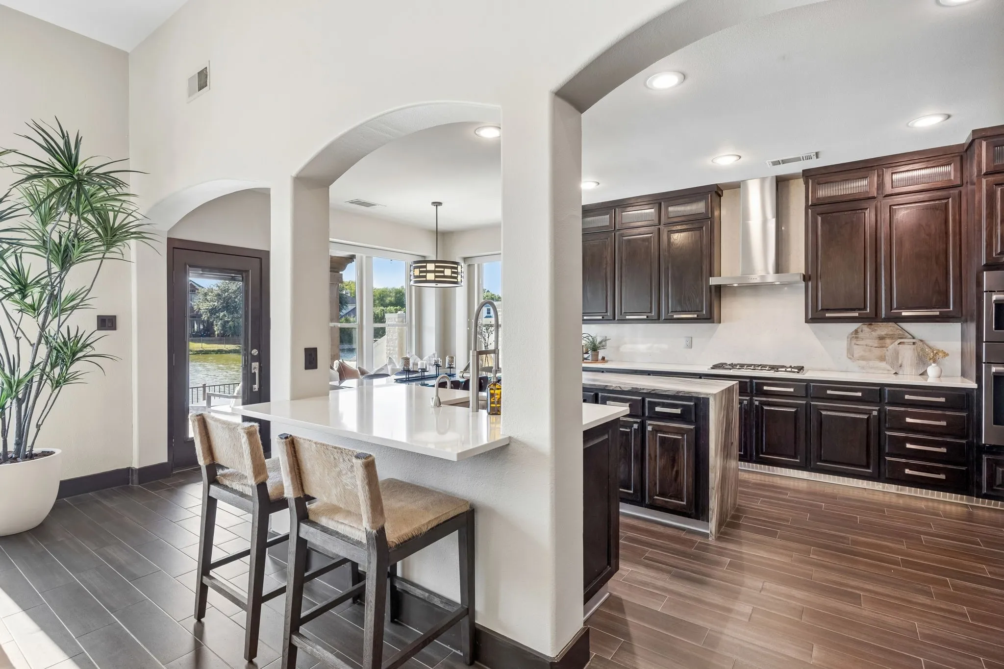 The kitchen offers rich wood cabinetry, quartz countertops, stainless steel appliances, gas cooking + a large center island