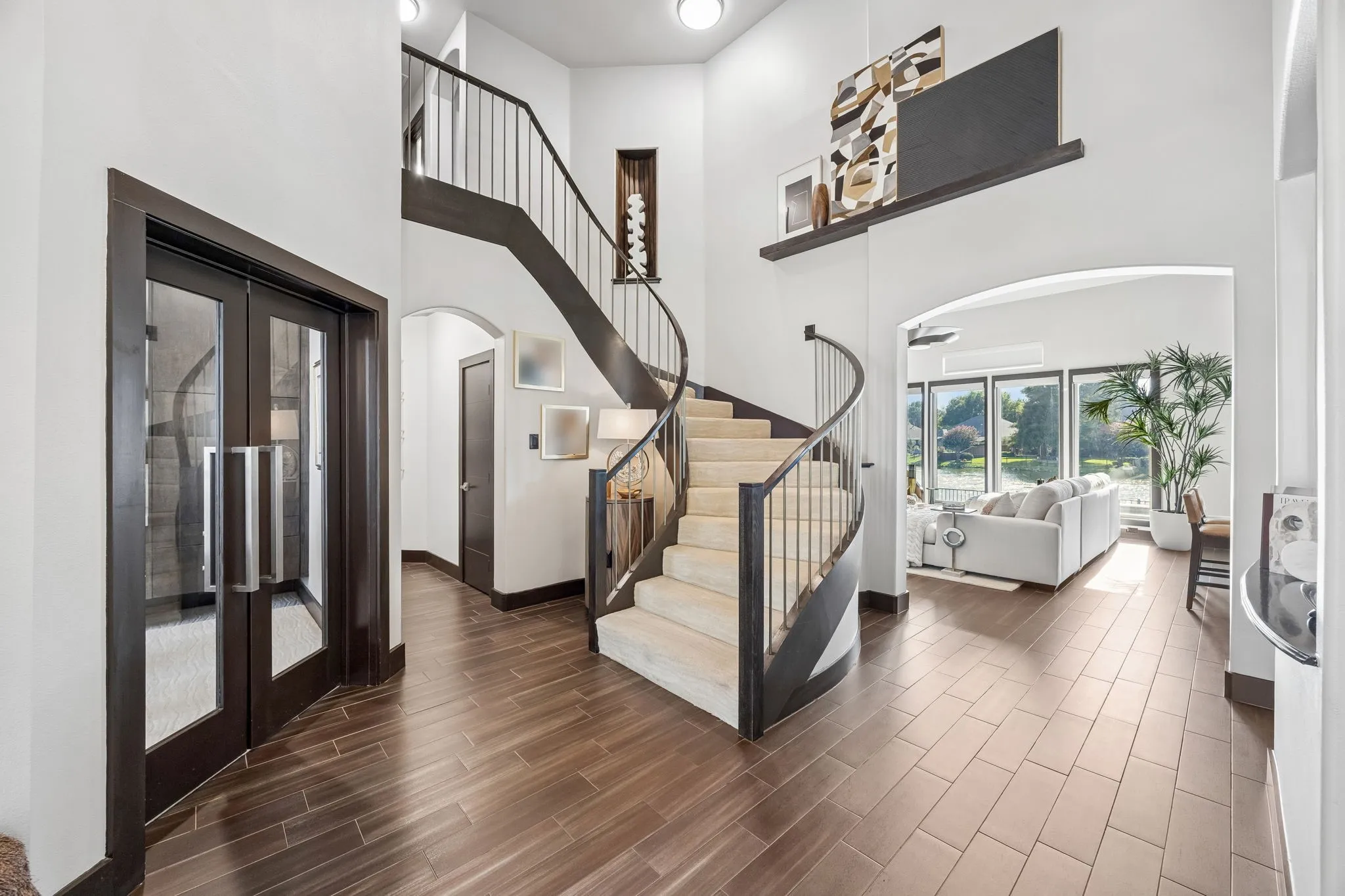 Upon entry, soaring ceilings, arched openings, abundant windows, and a dramatic curved staircase.
