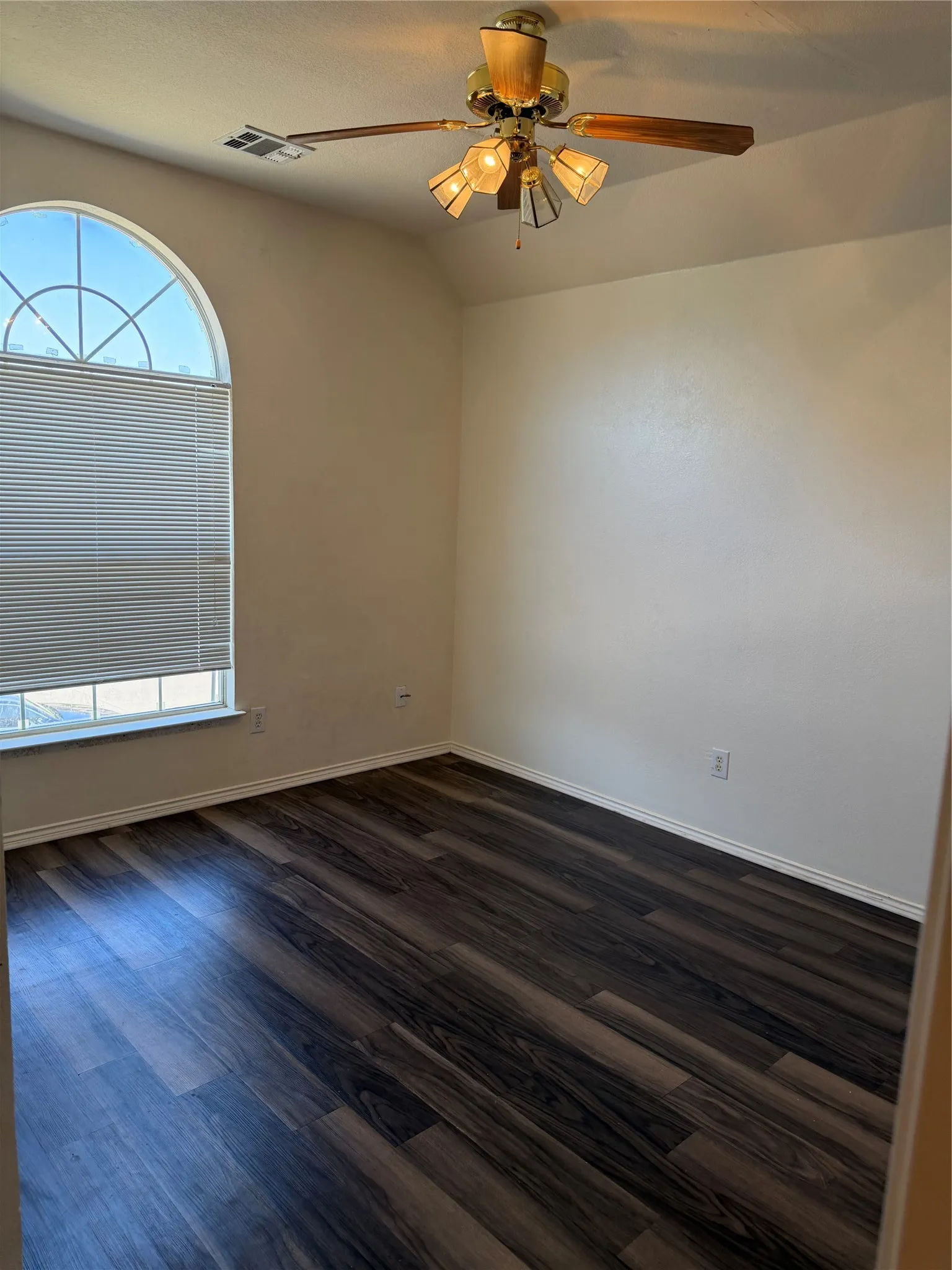 Arched window with blinds, wood-finish flooring, and a ceiling fan with integrated lighting
