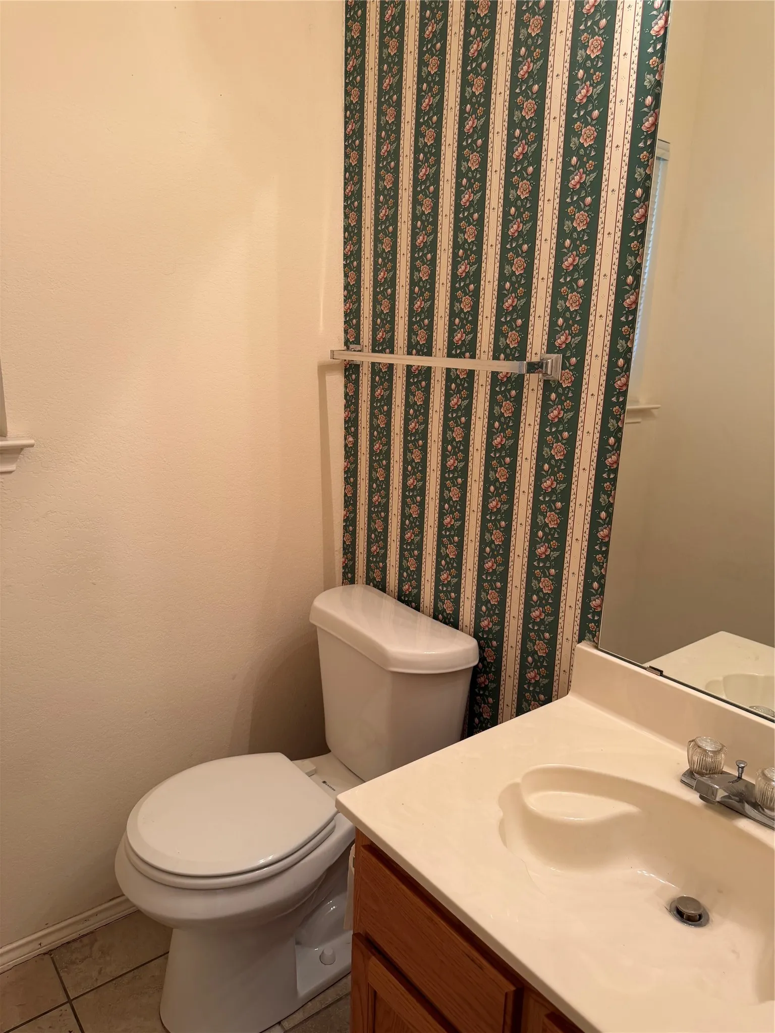 Bathroom featuring a vanity with a built-in sink, wood-finish cabinetry, and tiled flooring