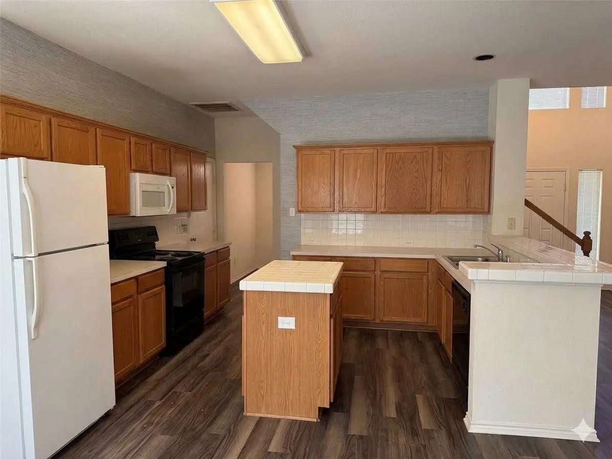 Open-concept kitchen featuring wood-finish flooring, white subway tile backsplash, white countertops, a central island, and wood cabinetry
