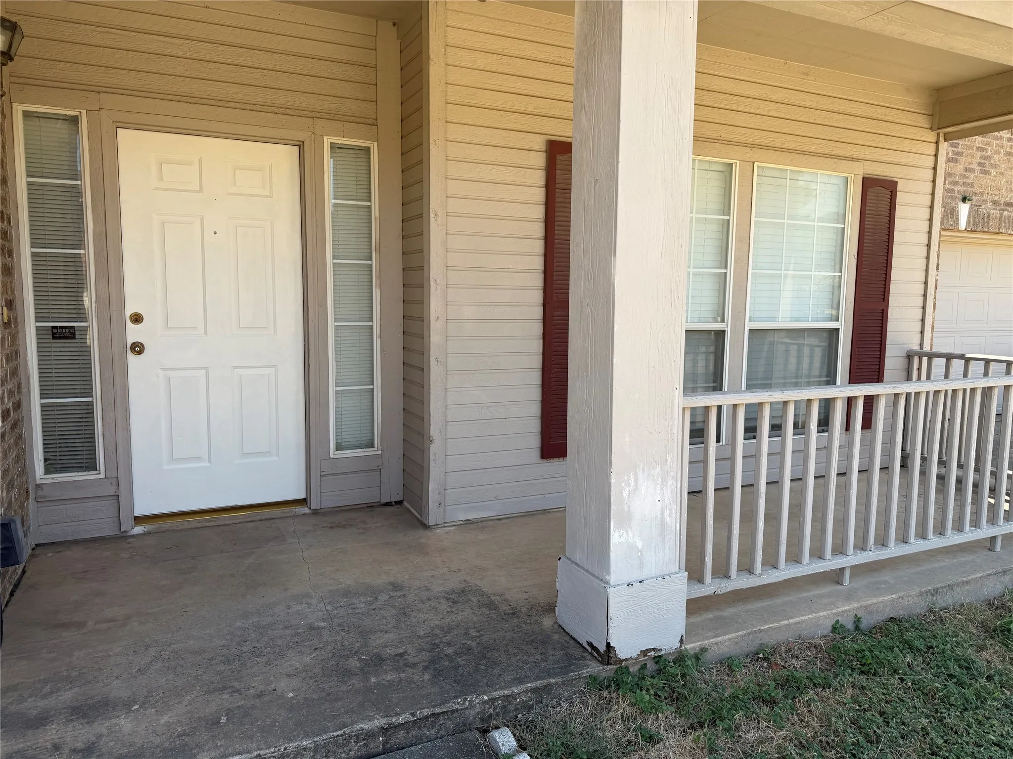 Covered front porch featuring a white panel door, sidelight windows, and a wood railing