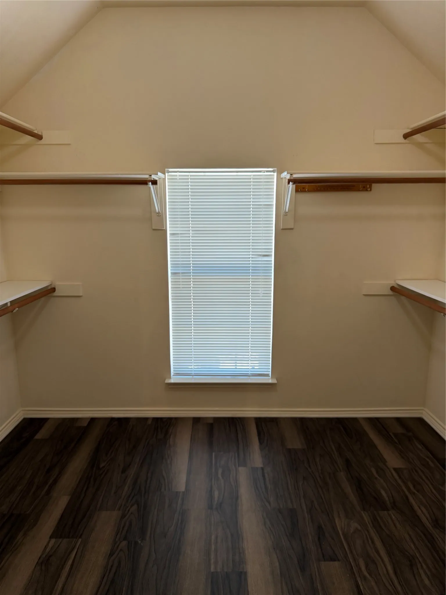 Wood-finish flooring, multiple shelving units, and a window with blinds