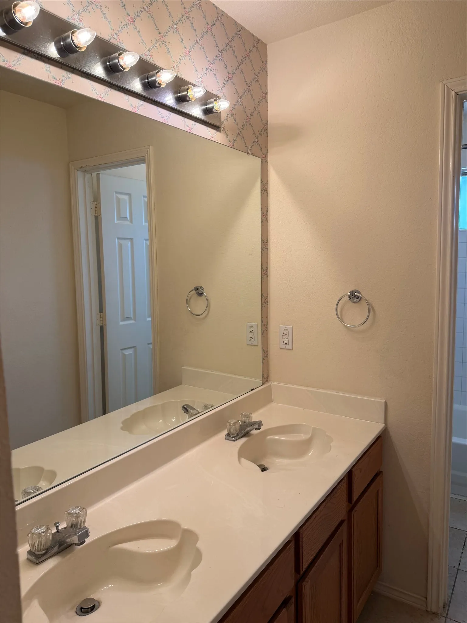Dual vanity with integrated sinks, wood-finish cabinetry, and a full-width mirror