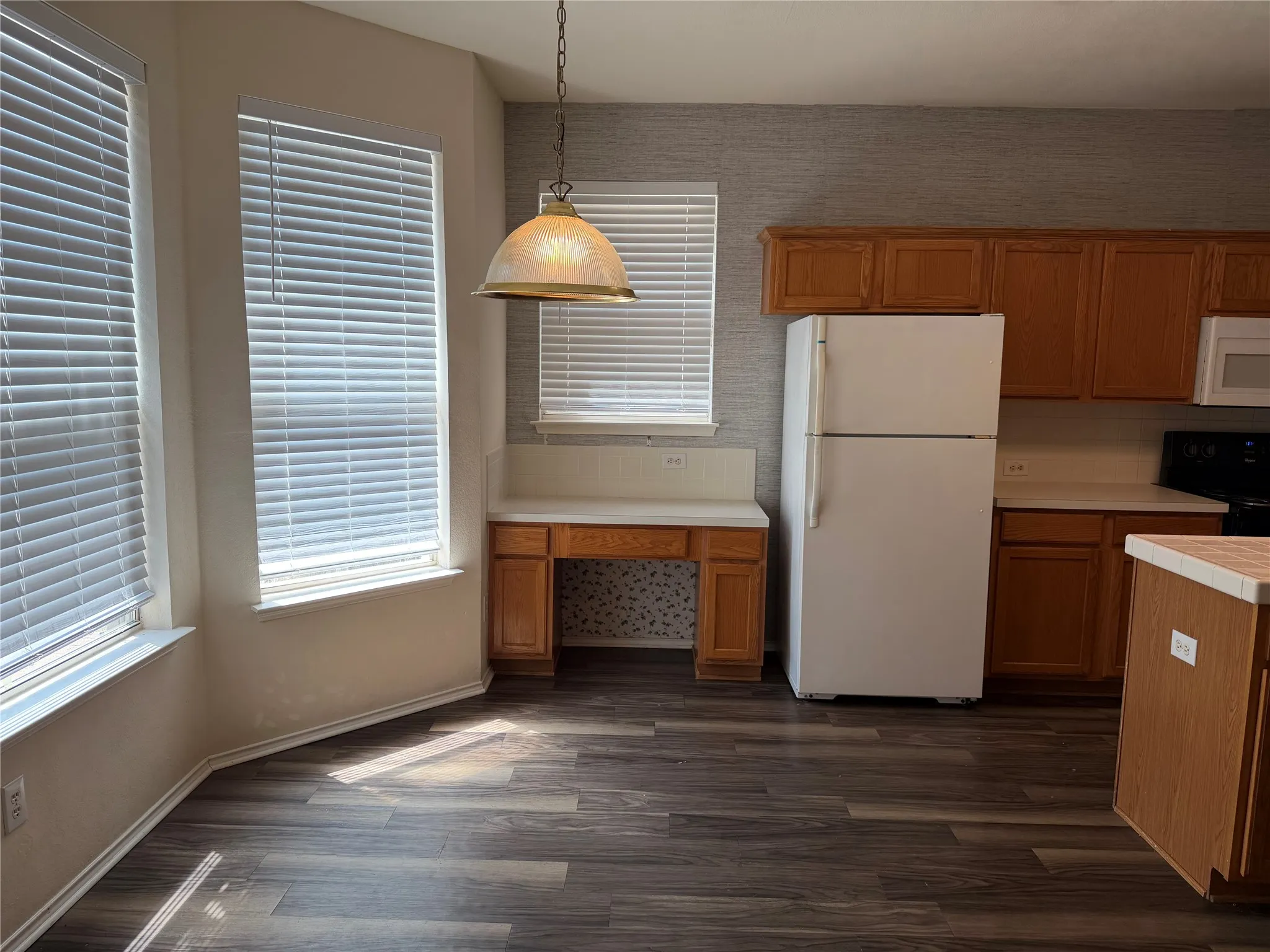 Spacious kitchen featuring wood cabinetry, stainless steel appliances, wood-finish flooring, and abundant natural light from multiple windows