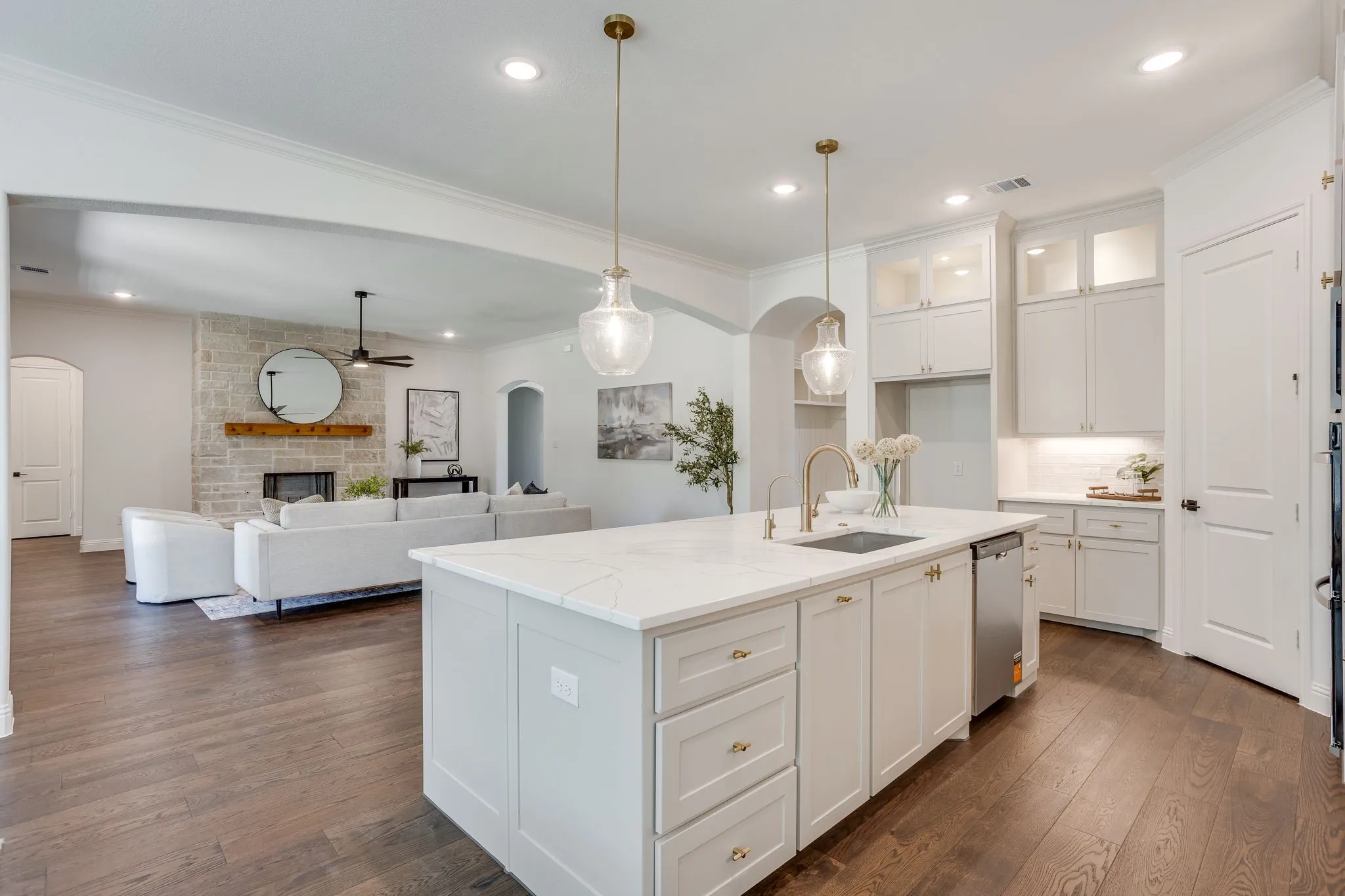 Gourmet kitchen with a large island, quartz countertops, white cabinetry with glass-front uppers, and stainless steel appliances