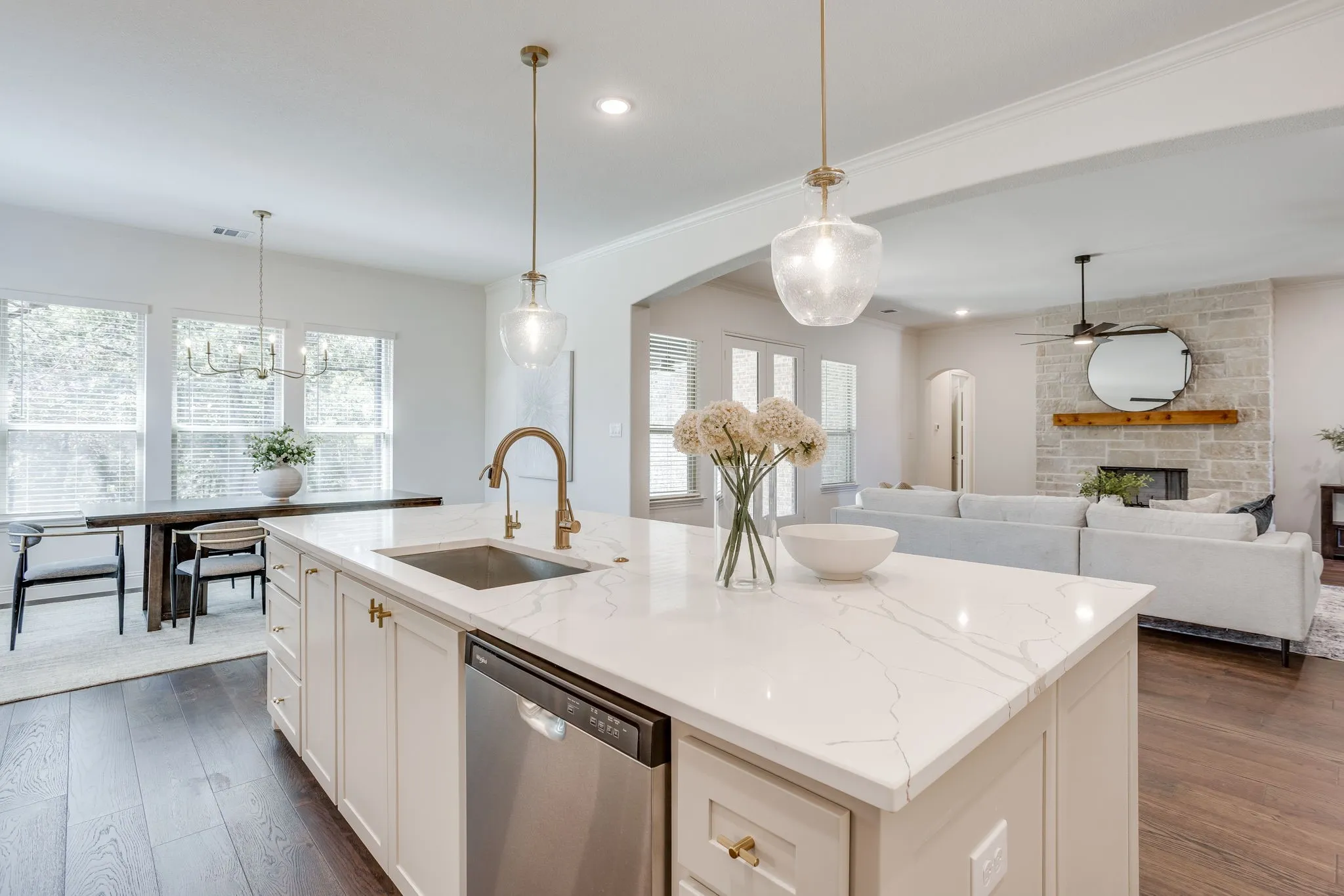 Kitchen island featuring a single basin sink, brass-finish faucet, and integrated dishwasher