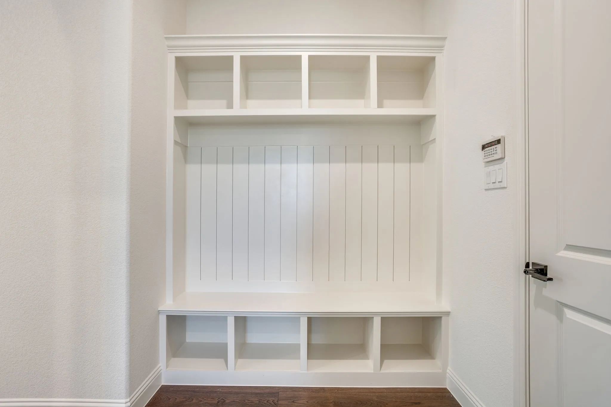 Built-in custom cabinetry, upper shelving, lower storage compartments, and a built-in bench