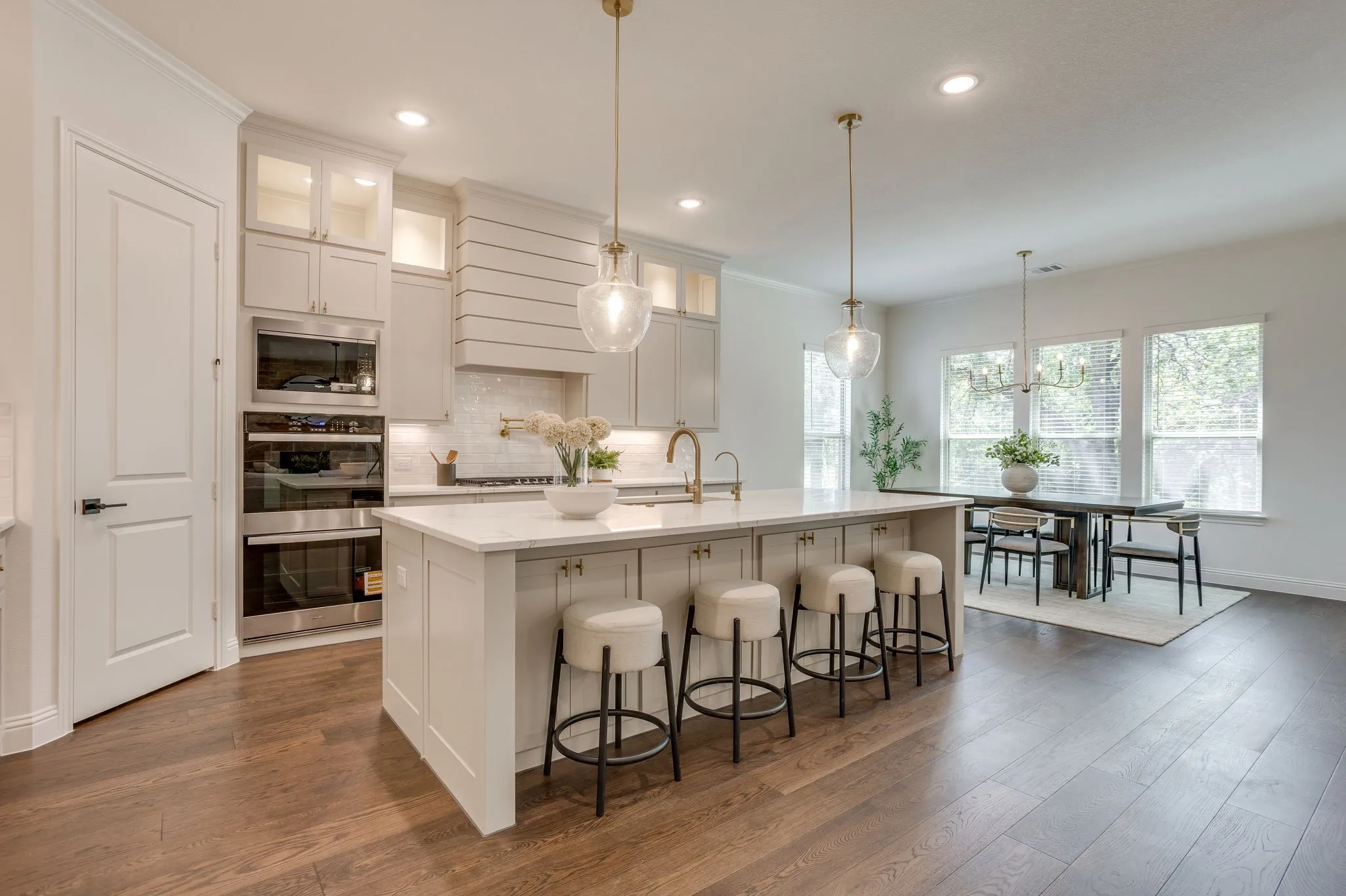 Open-concept kitchen with a large island, wood-finish flooring, stainless steel built-in appliances, and recessed lighting
