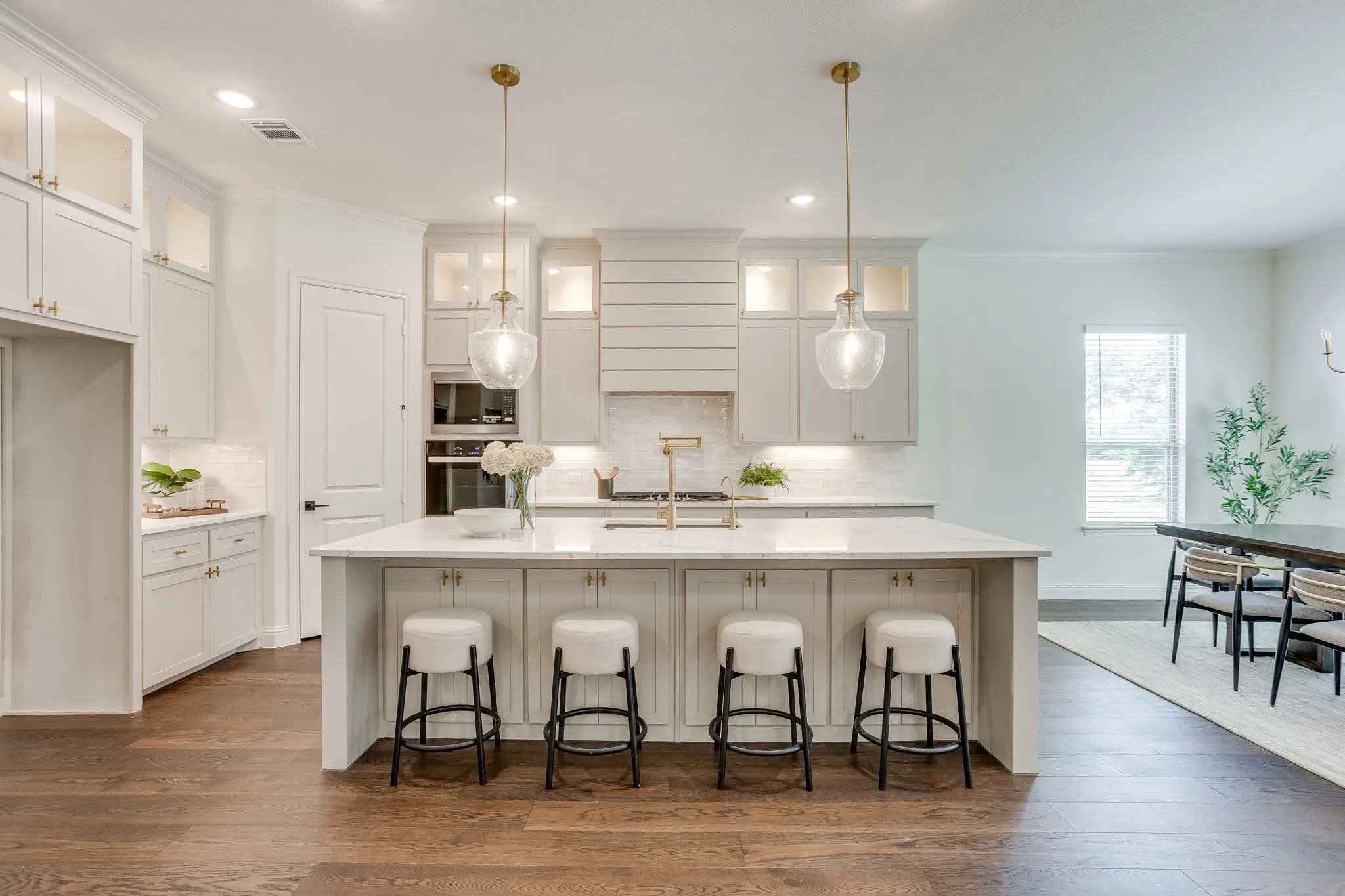 Kitchen featuring a large center island, built-in appliances, custom cabinetry, and wood-finish flooring