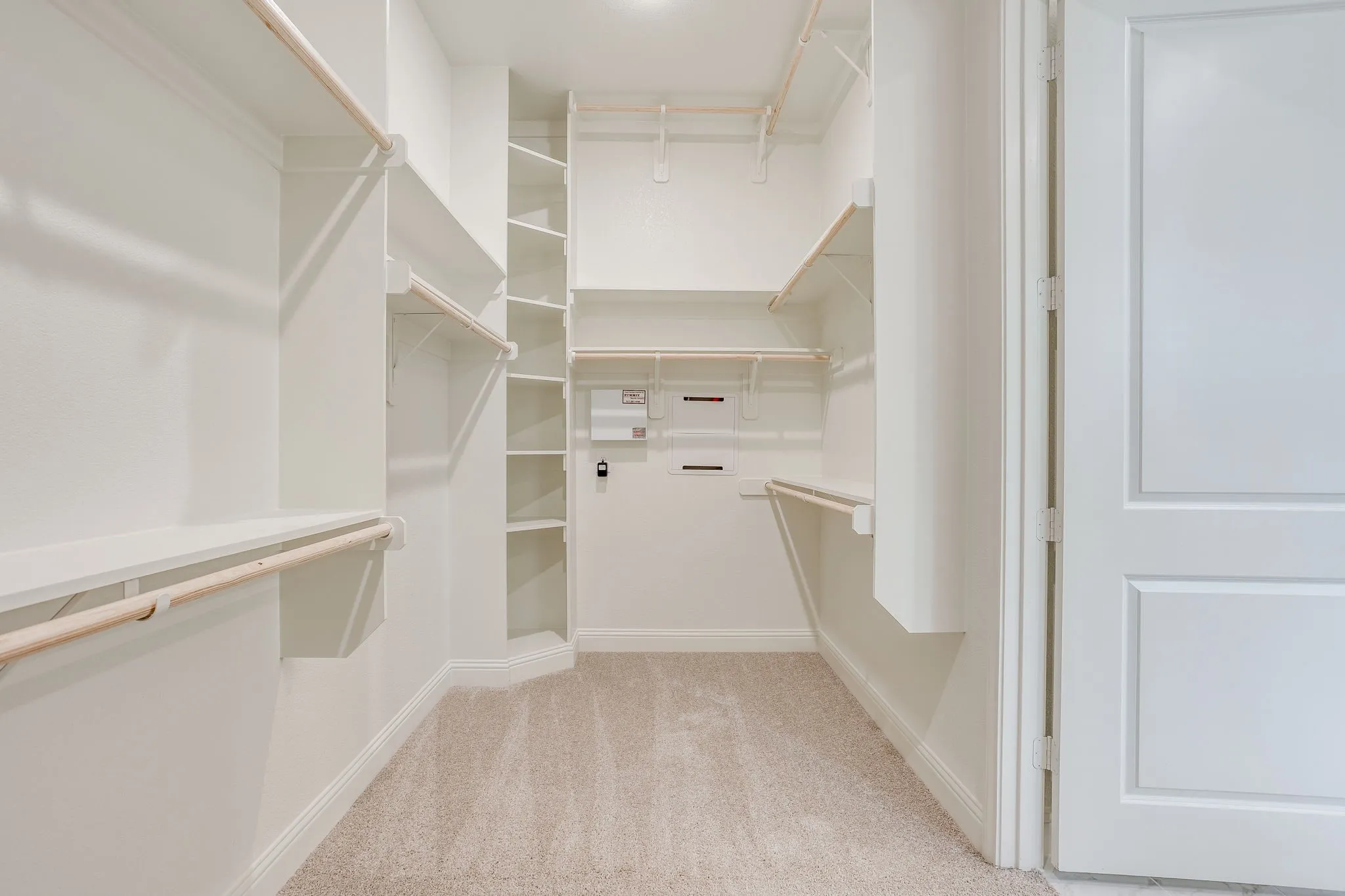 Walk-in closet extensive built-in shelving, and multiple hanging rods