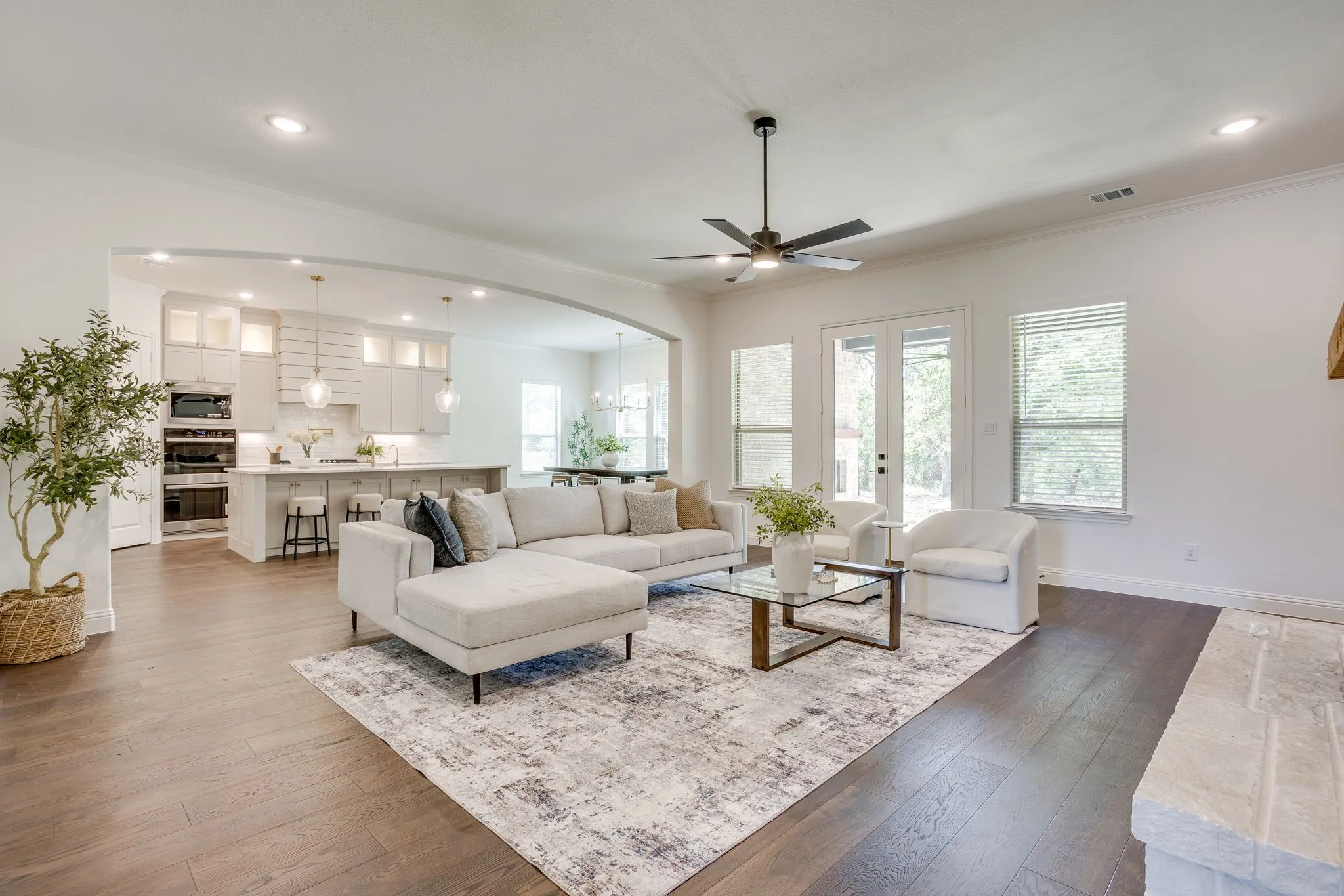Expansive living area with wood-finish flooring, recessed lighting, and a modern ceiling fan