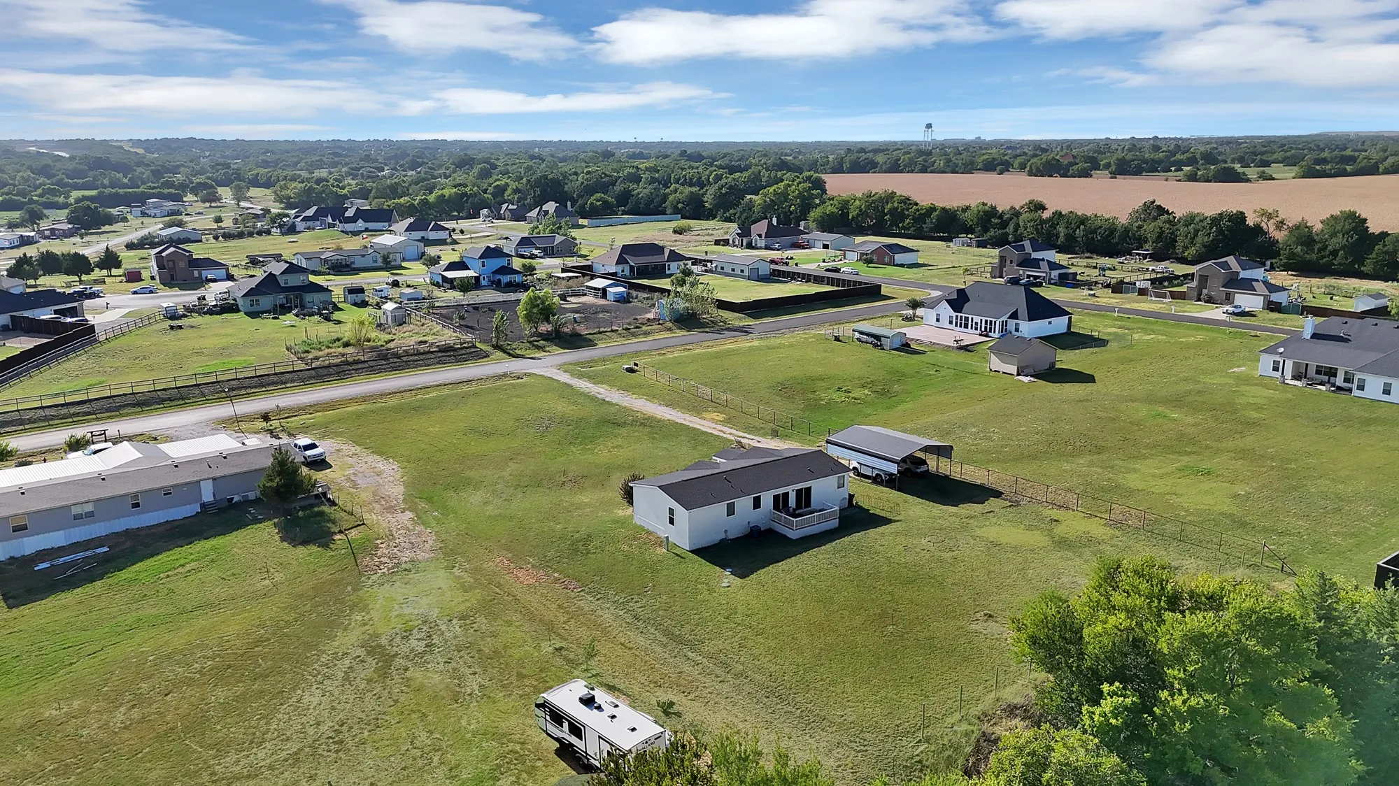 Expansive grassy lot featuring a single-story home with a covered porch and an attached carport