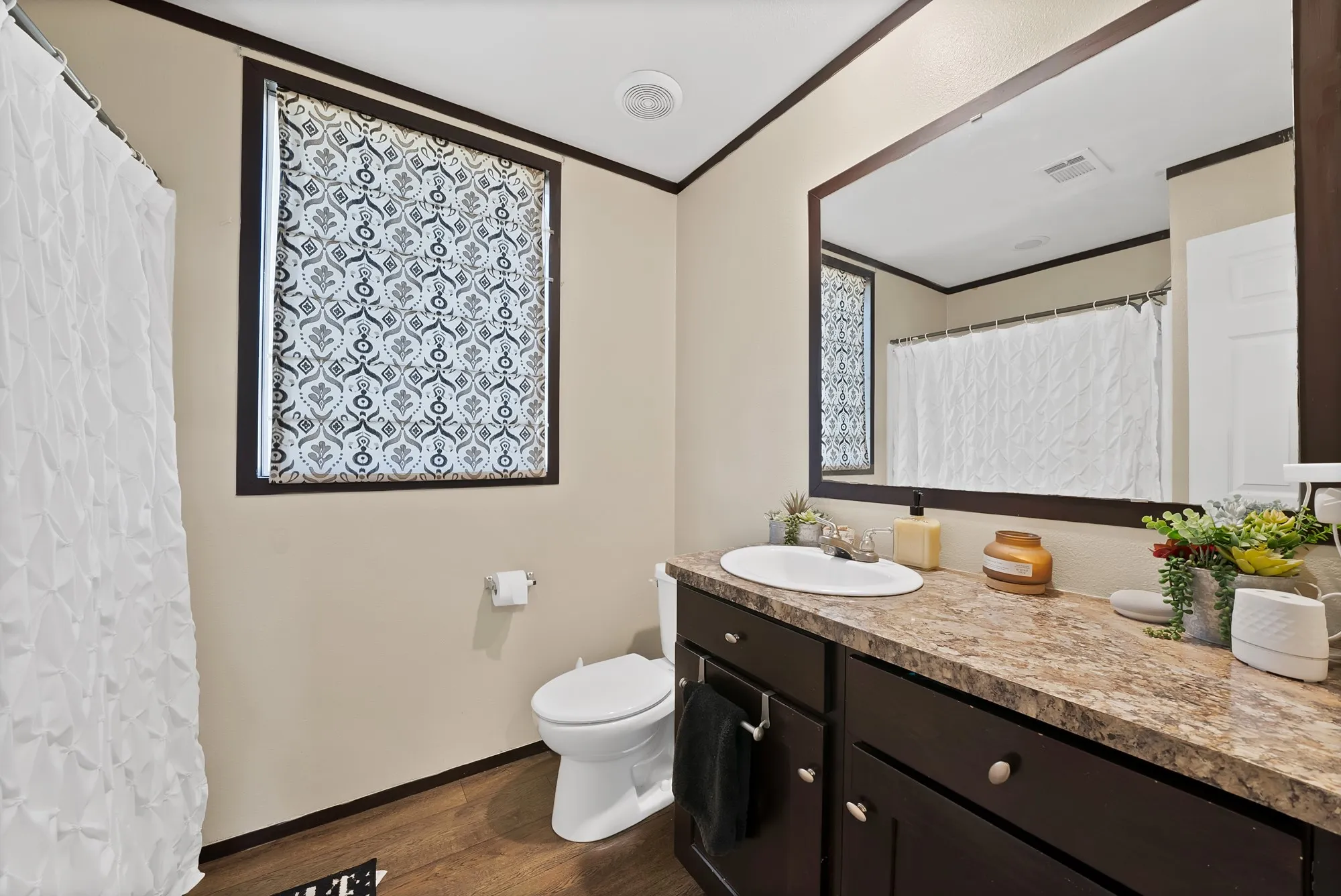 Expansive vanity with an integrated sink, framed mirror, and dark wood-finish cabinetry