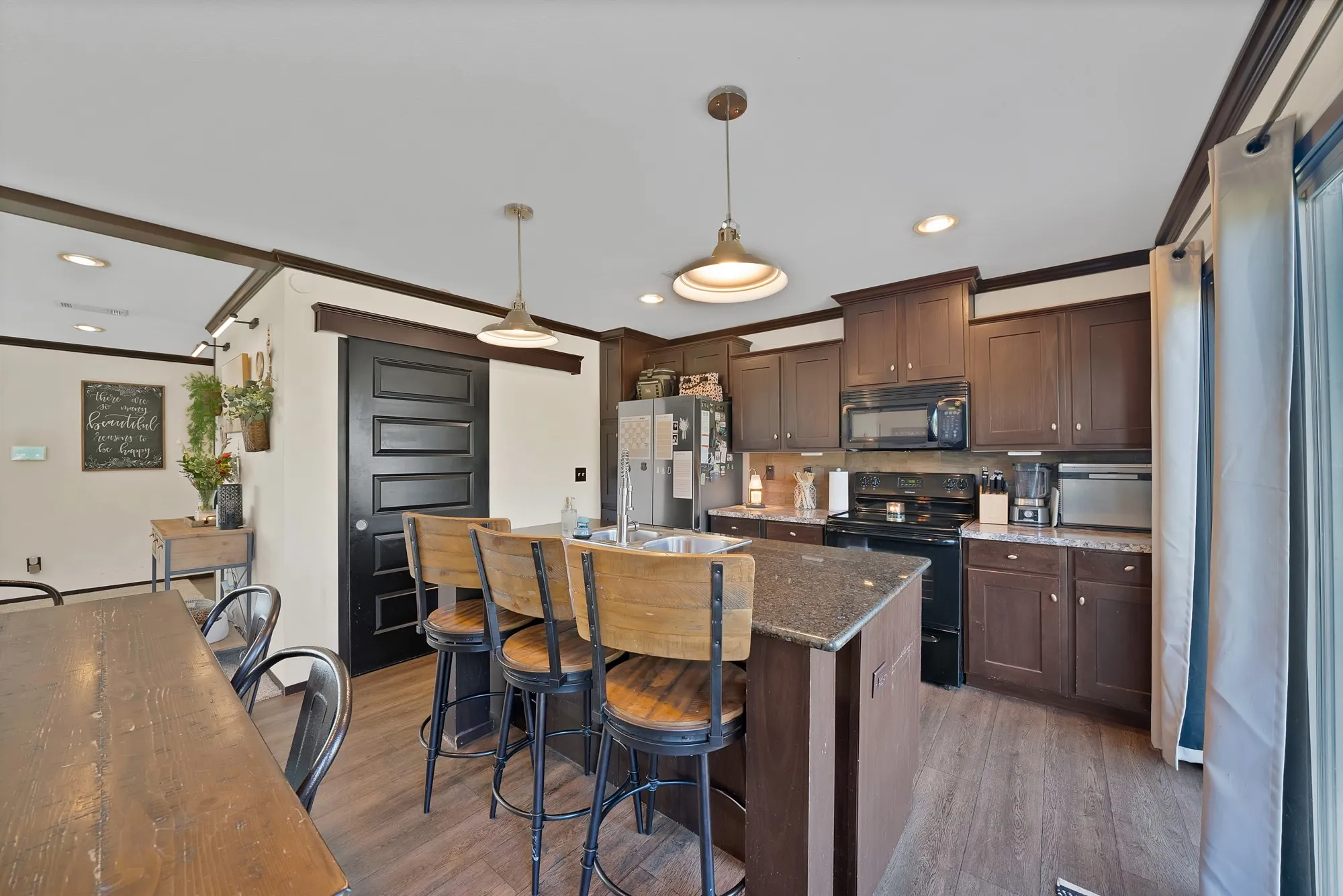 Kitchen featuring dark wood cabinetry, granite-style countertops, stainless steel appliances, and wood-finish flooring