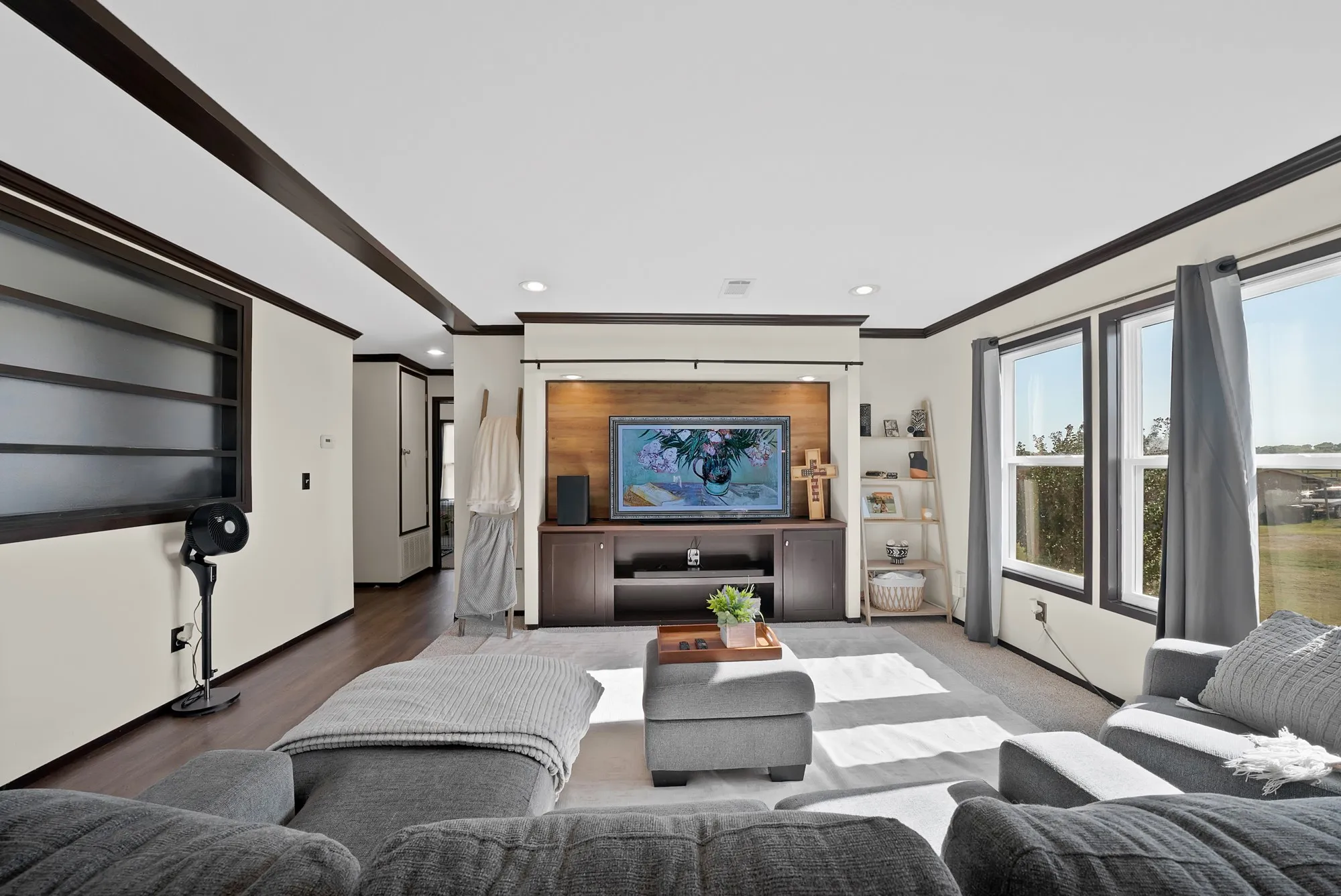 Expansive living area with wood-finish flooring, recessed lighting, and large windows