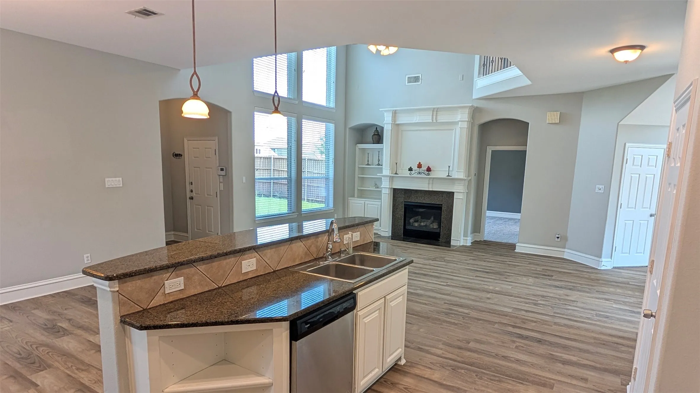 Kitchen island with granite-finish countertop, dual basin sink, and integrated dishwasher