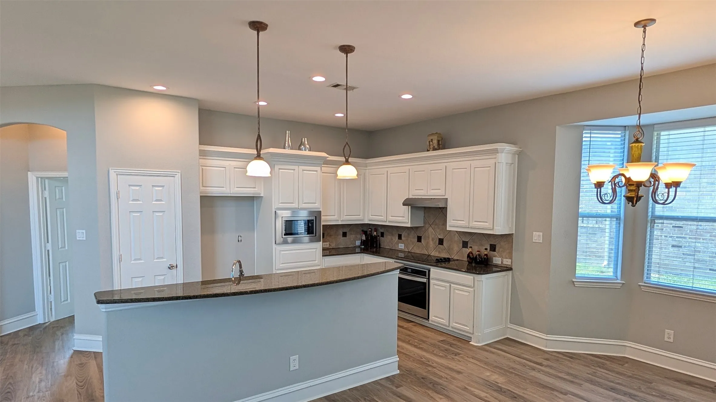 Kitchen featuring white cabinetry, dark countertops, a tiled backsplash, and stainless steel appliances