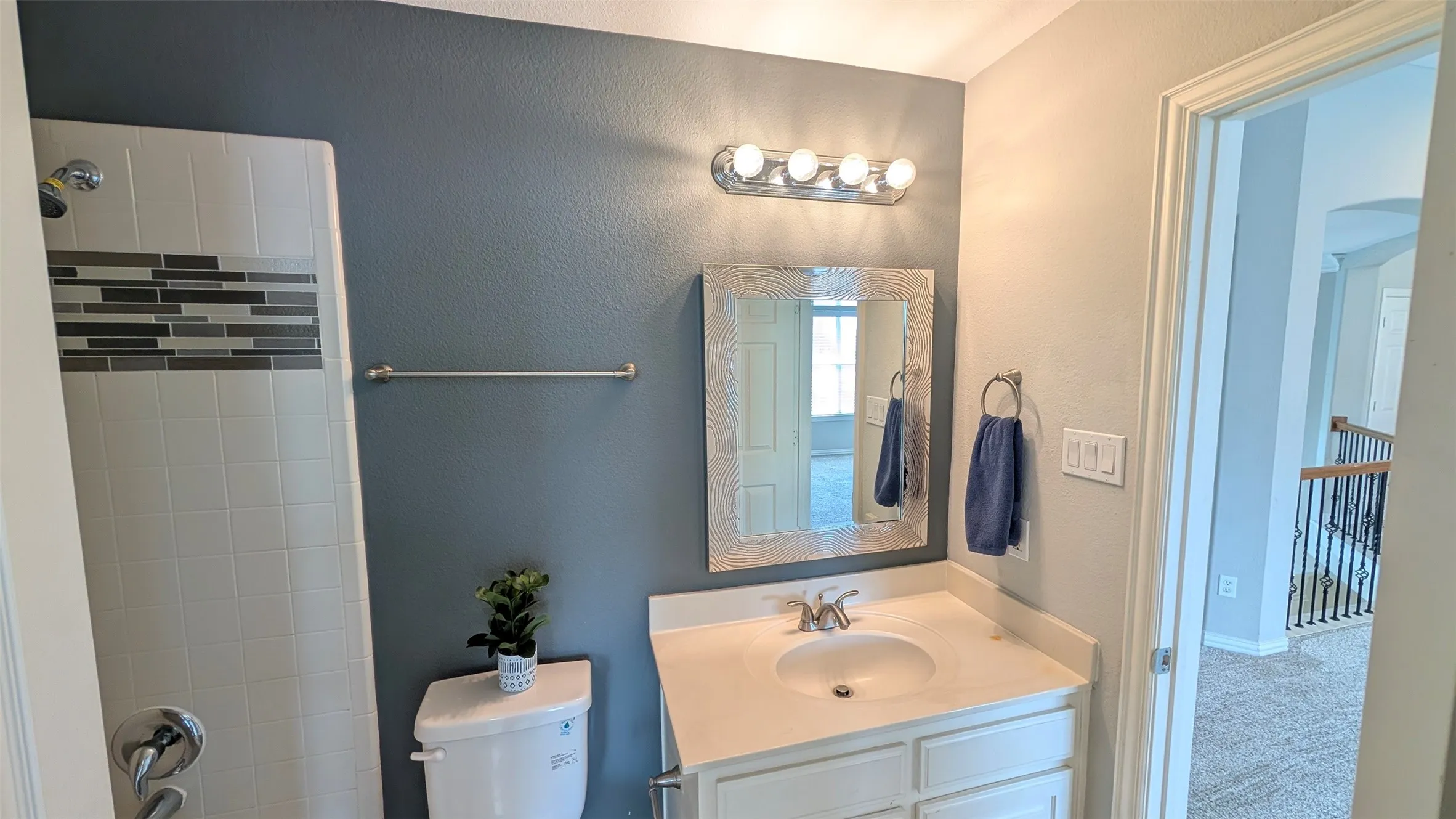 Vanity with an integrated sink, polished chrome faucet, and overhead bar lighting